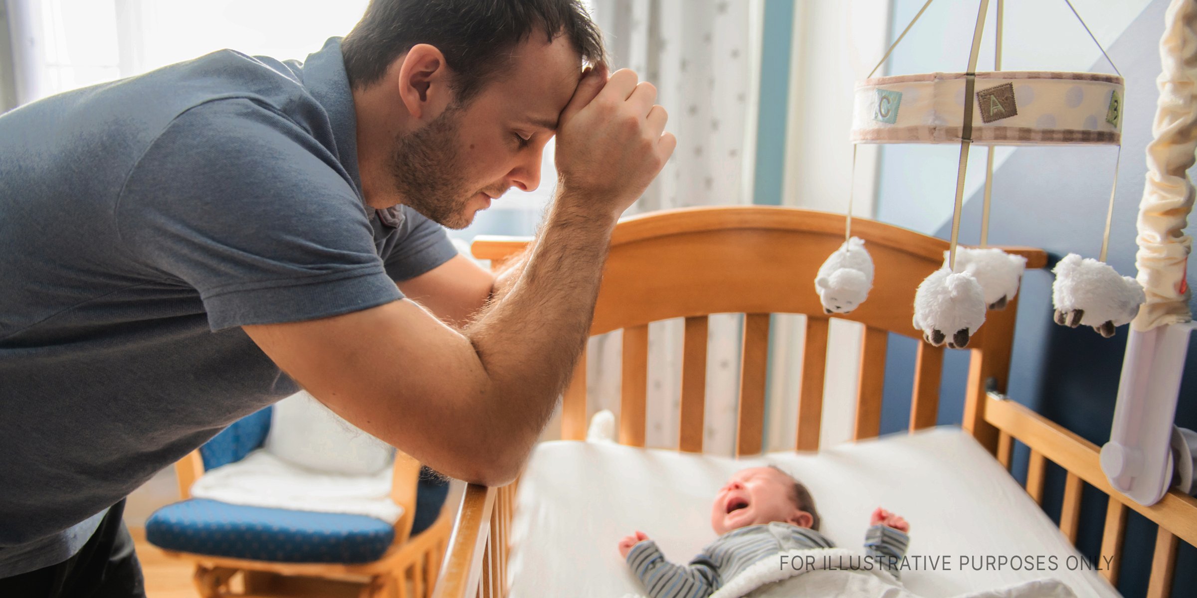 Ein Mann blickt auf ein Baby in einem Kinderbett. | Quelle: Shutterstock