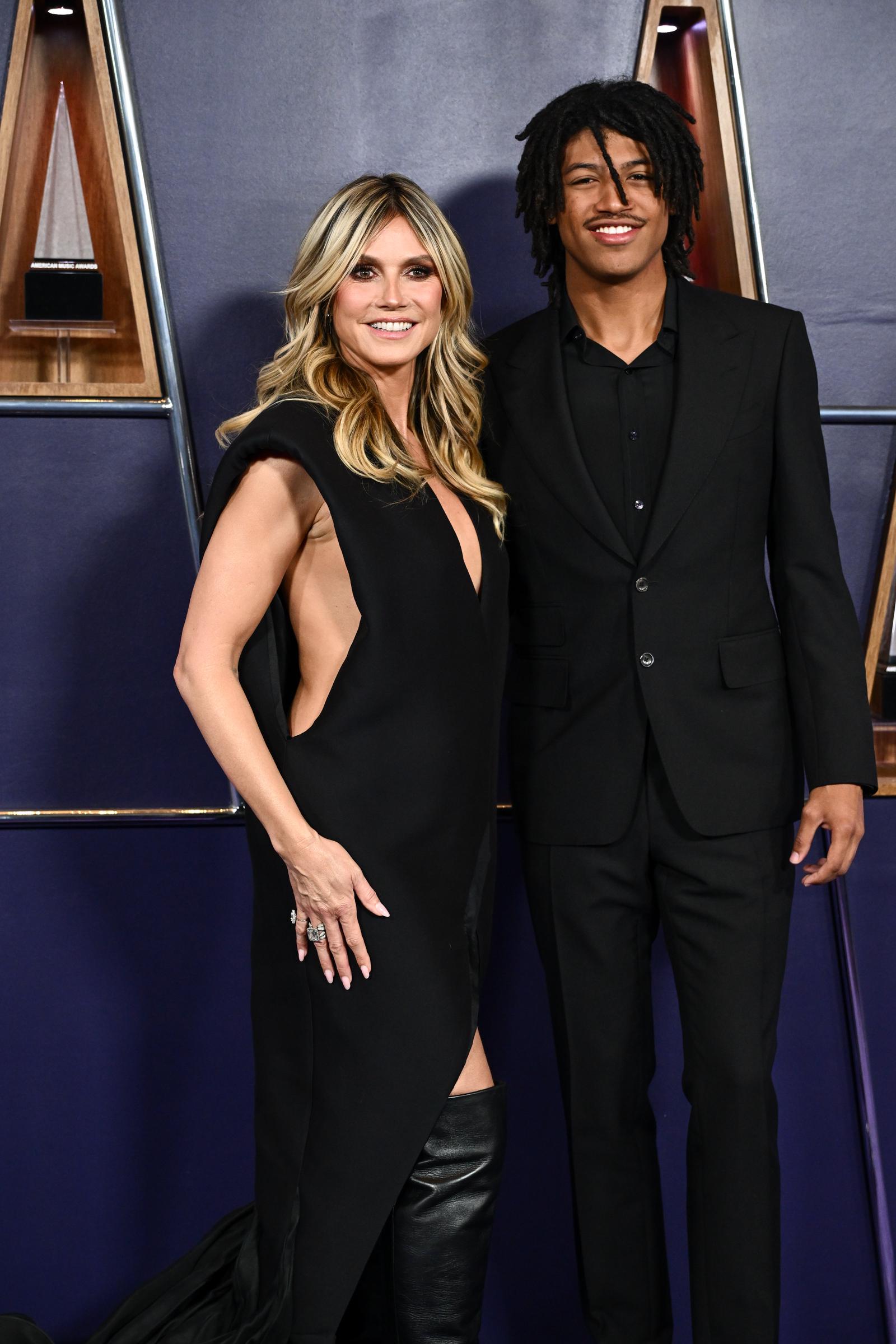 Heidi Klum und ihr Sohn Henry Samuel stehen Arm in Arm auf dem lila Teppich der AMAs. Die klaren Linien ihres Kleides und sein maßgeschneiderter Anzug sorgten für ein gelungenes Familienfoto im Scheinwerferlicht.