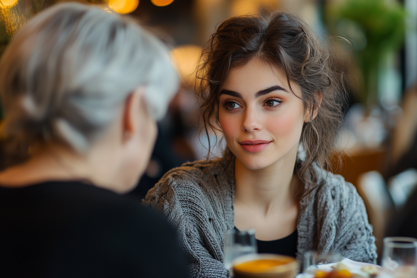 Eine Frau, die sich beim Mittagessen mit ihrer Schwiegermutter unterhält | Quelle: Midjourney