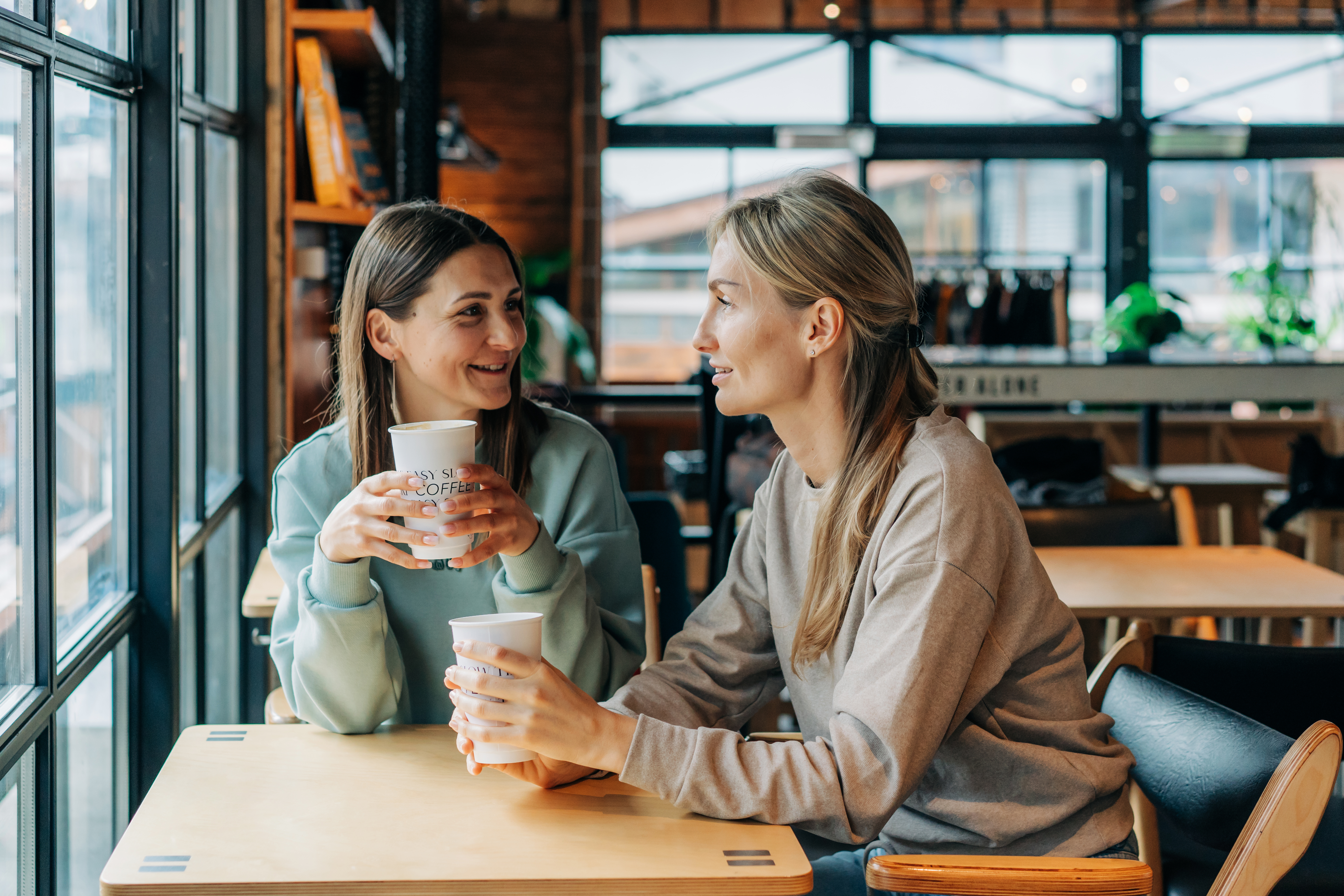 Zwei Frauen sitzen in einem Kaffeehaus, unterhalten sich und trinken Kaffee | Quelle: Getty Images