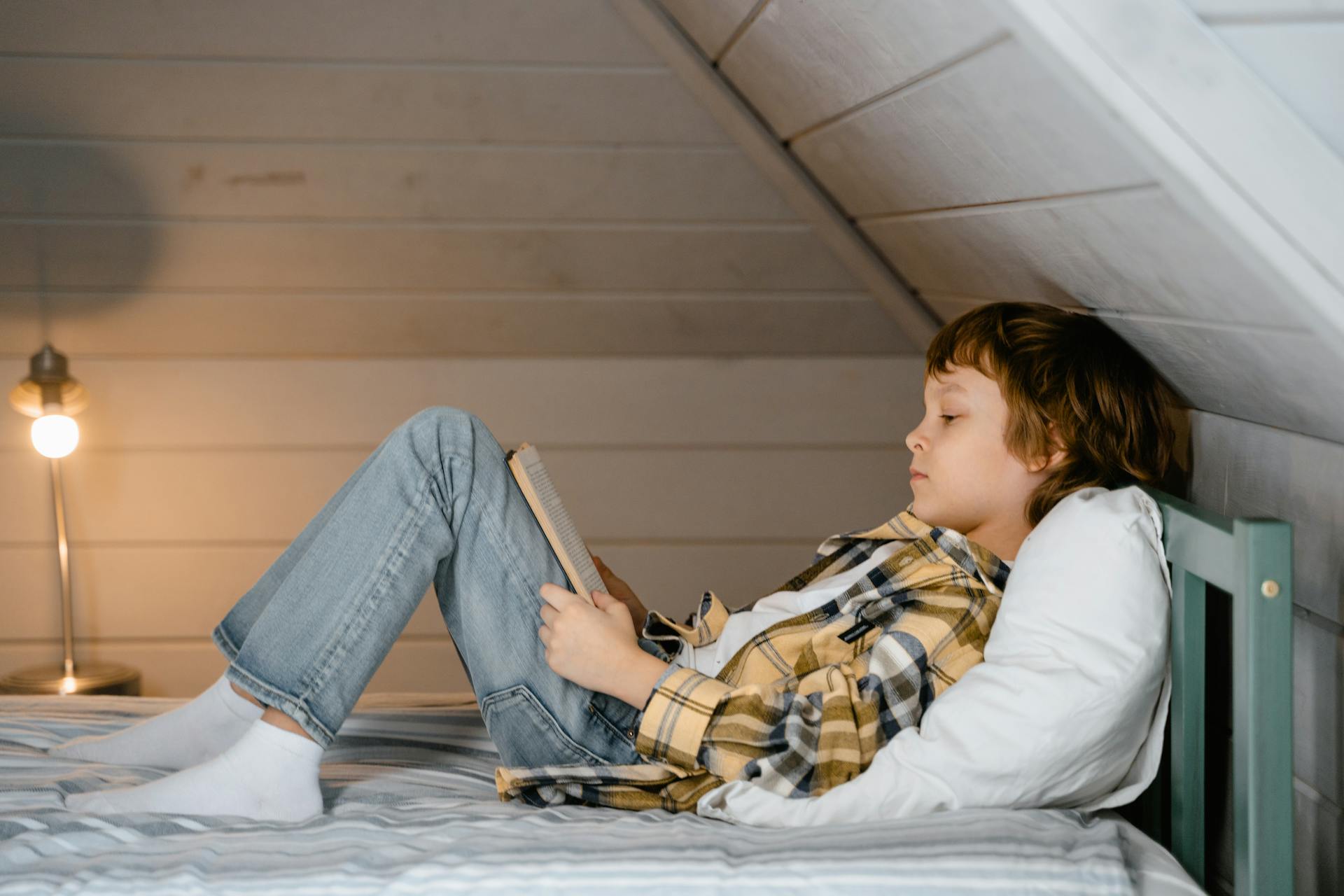 Ein Junge liest auf seinem Bett | Quelle: Pexels