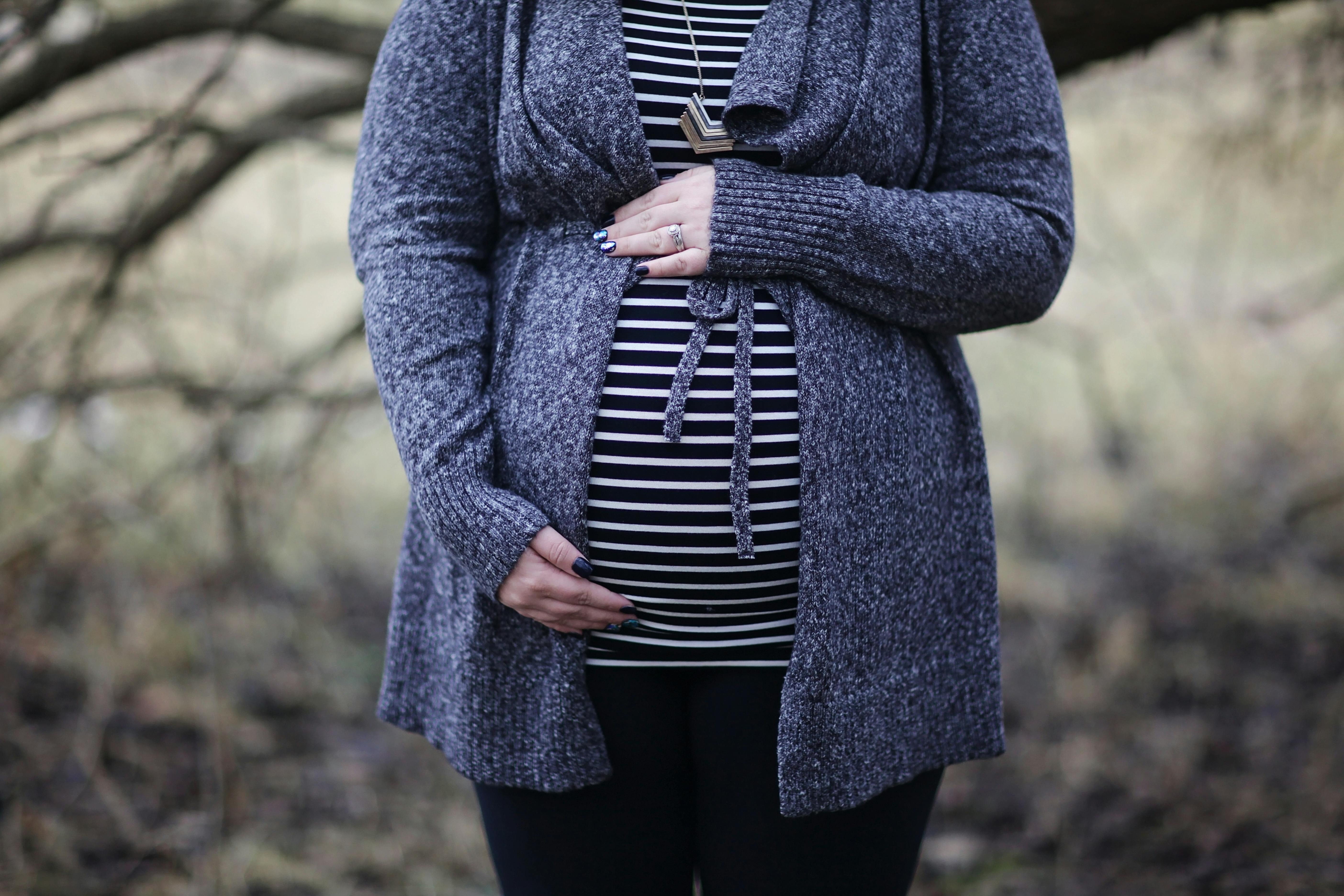 Eine schwangere Frau steht neben einem Baum. | Quelle: Pexels