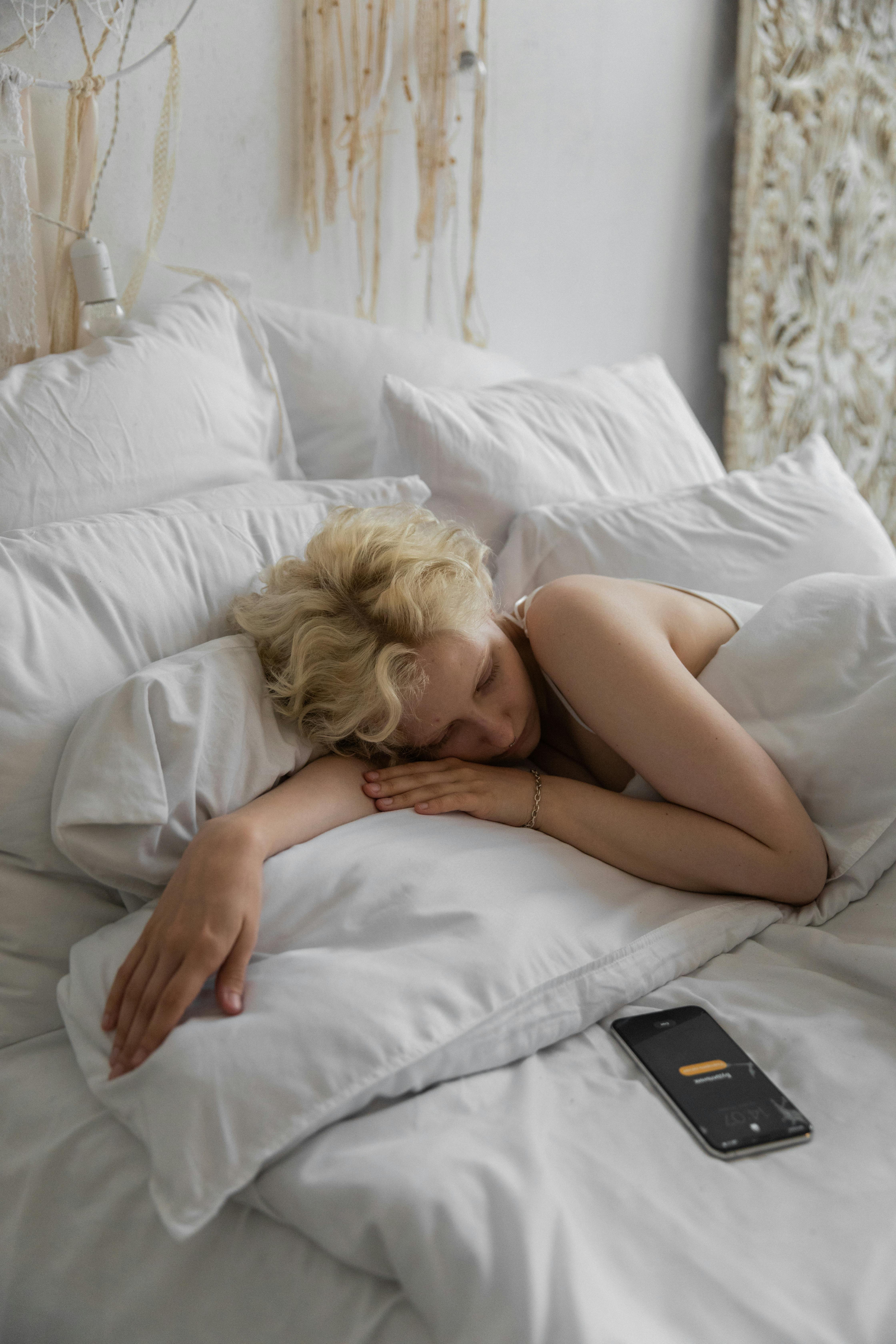 Eine Frau im Bett, die ihr Telefon unbeaufsichtigt lässt | Quelle: Pexels