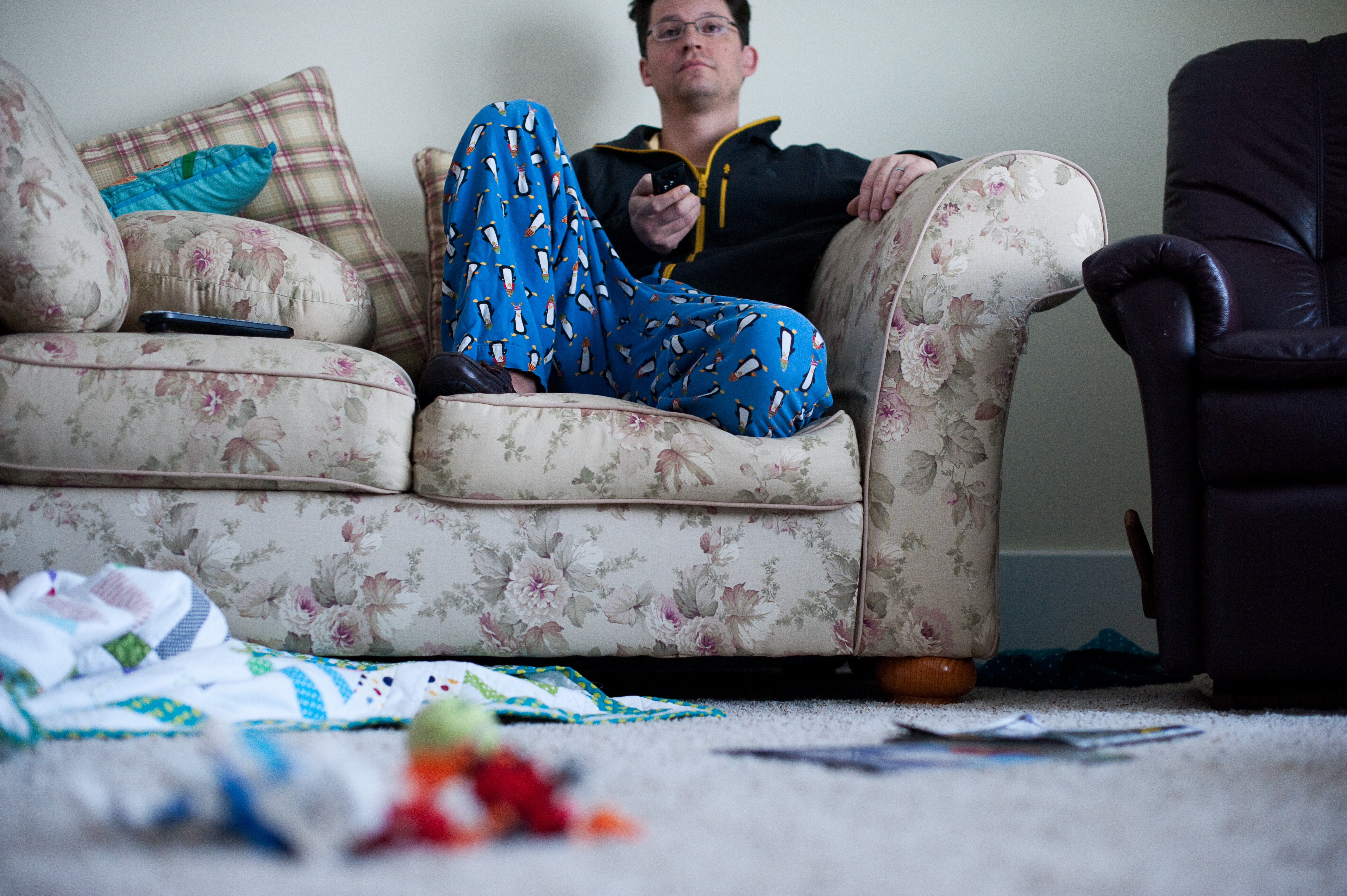 Ein fauler Mann, der vor dem Fernseher sitzt und ein unordentliches Haus hat | Quelle: Getty Images