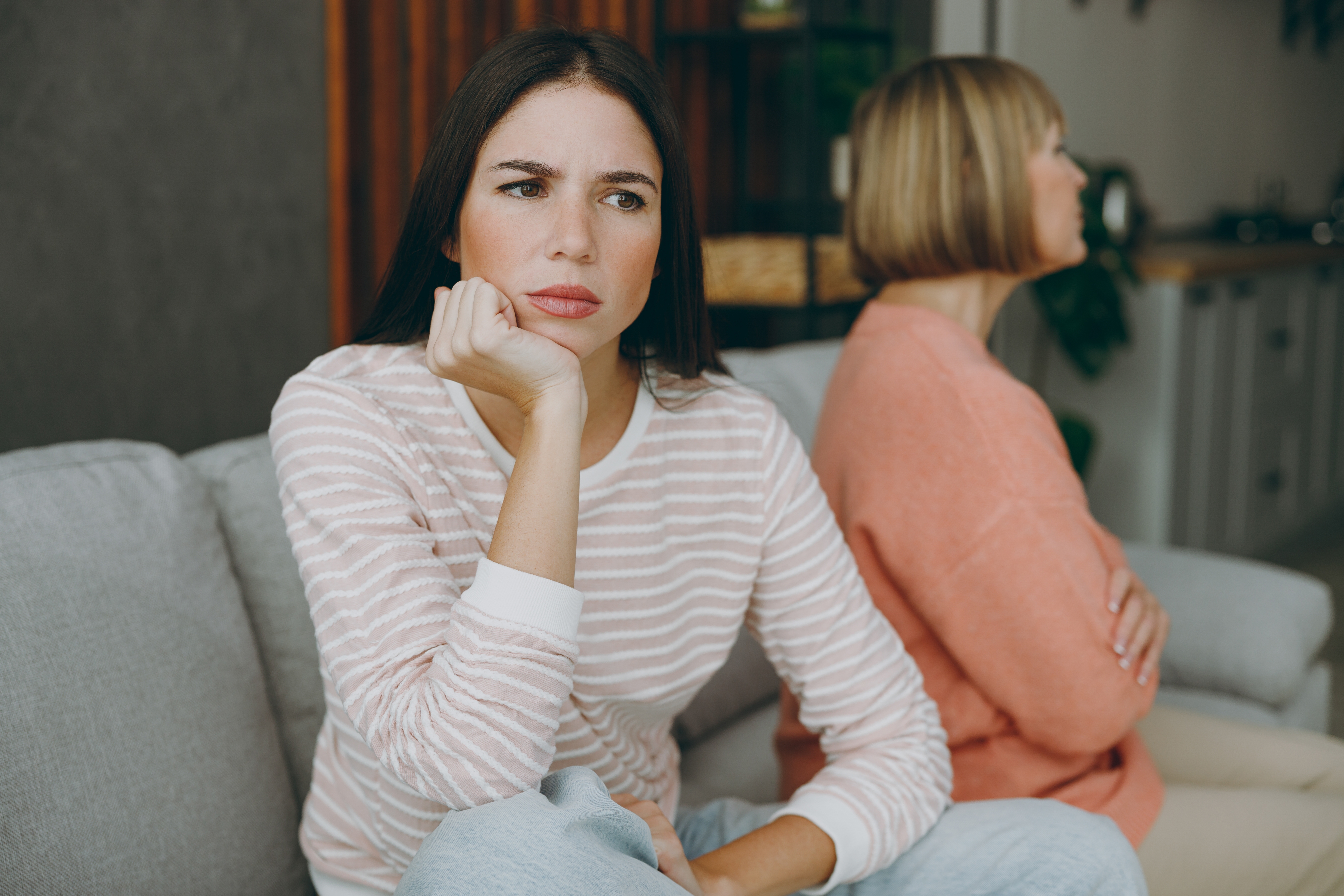 Eine ältere Frau und ihre Tochter sitzen nach einer Meinungsverschiedenheit nebeneinander | Quelle: Shutterstock