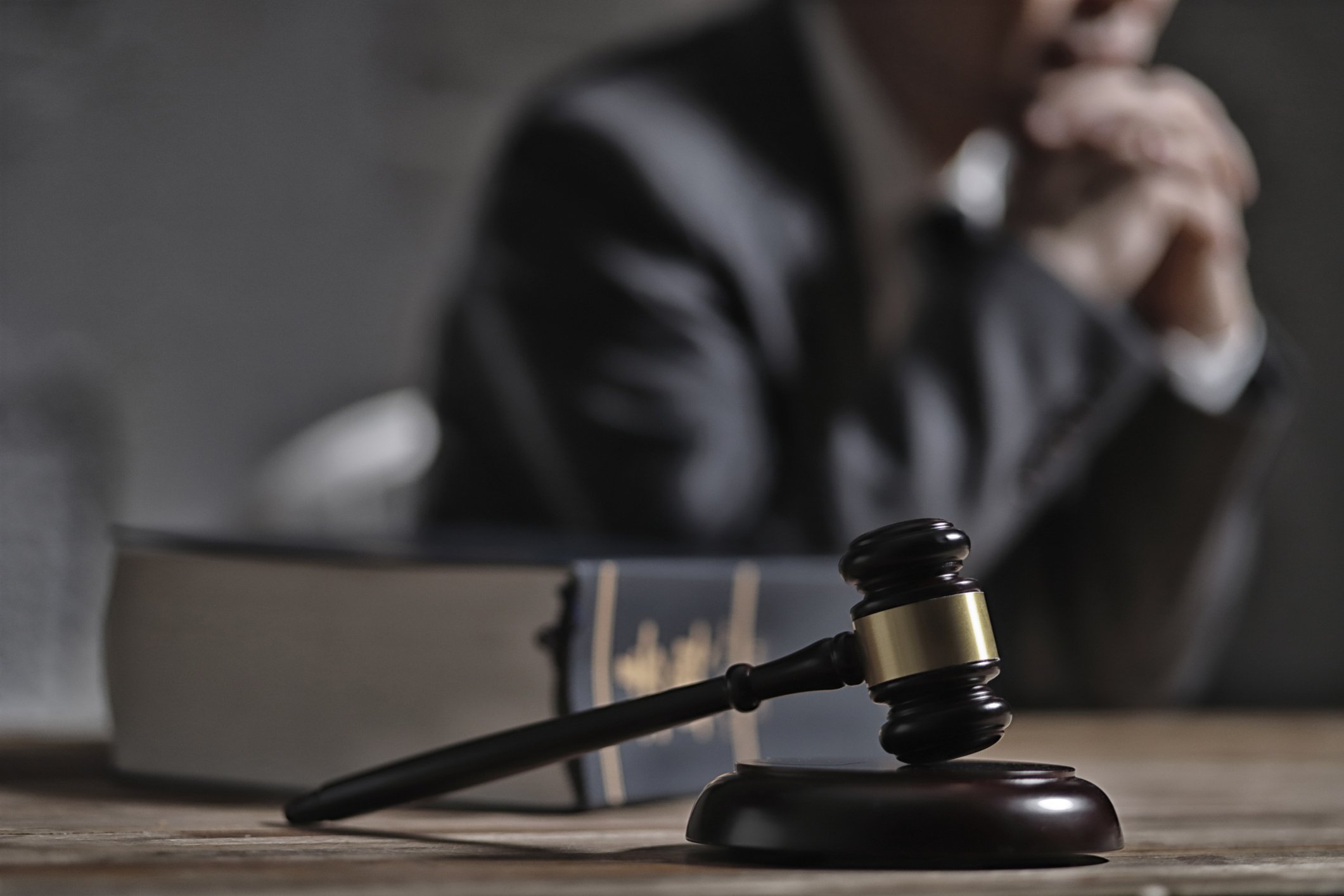 Richterhammer und Gesetzbuch vor Anwalt | Quelle: Getty Images
