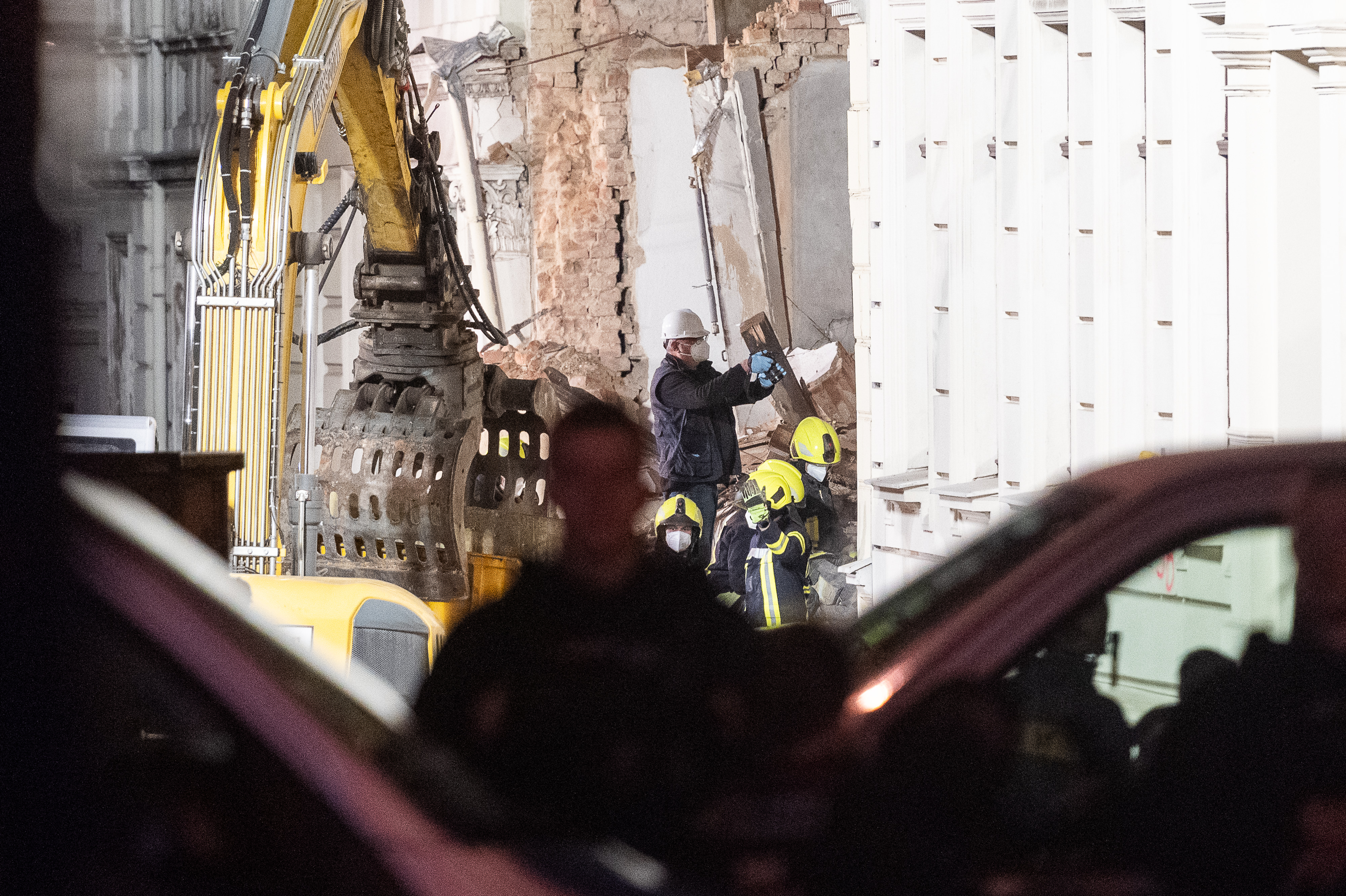 Eine Person macht ein Foto auf einem Trümmerhaufen, während die Rettungskräfte nach dem Einsturz eines Hauses weiterhin Trümmer beseitigen | Quelle: Getty Images