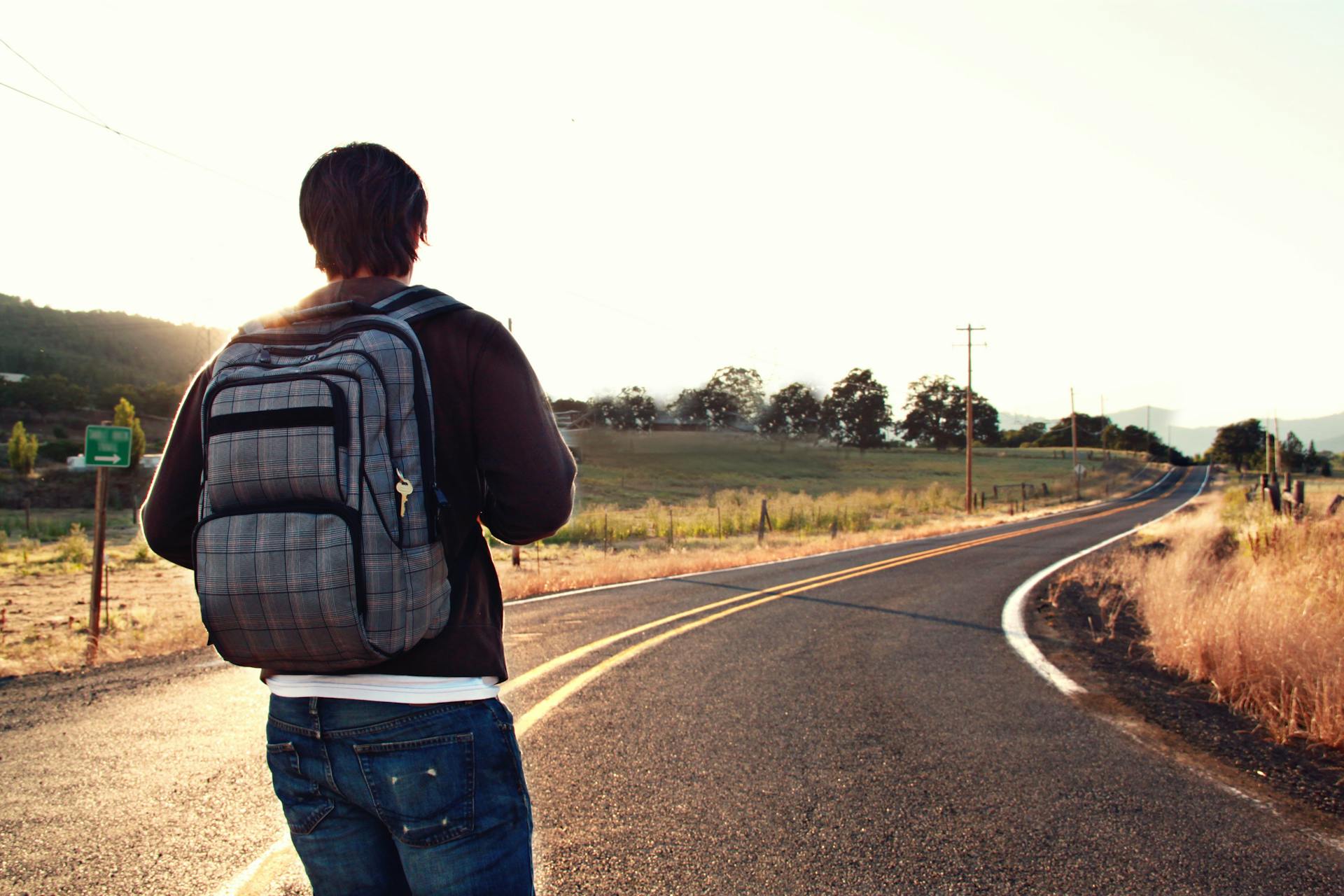 Ein Mann mit einem Rucksack steht auf einer Straße | Quelle: Pexels