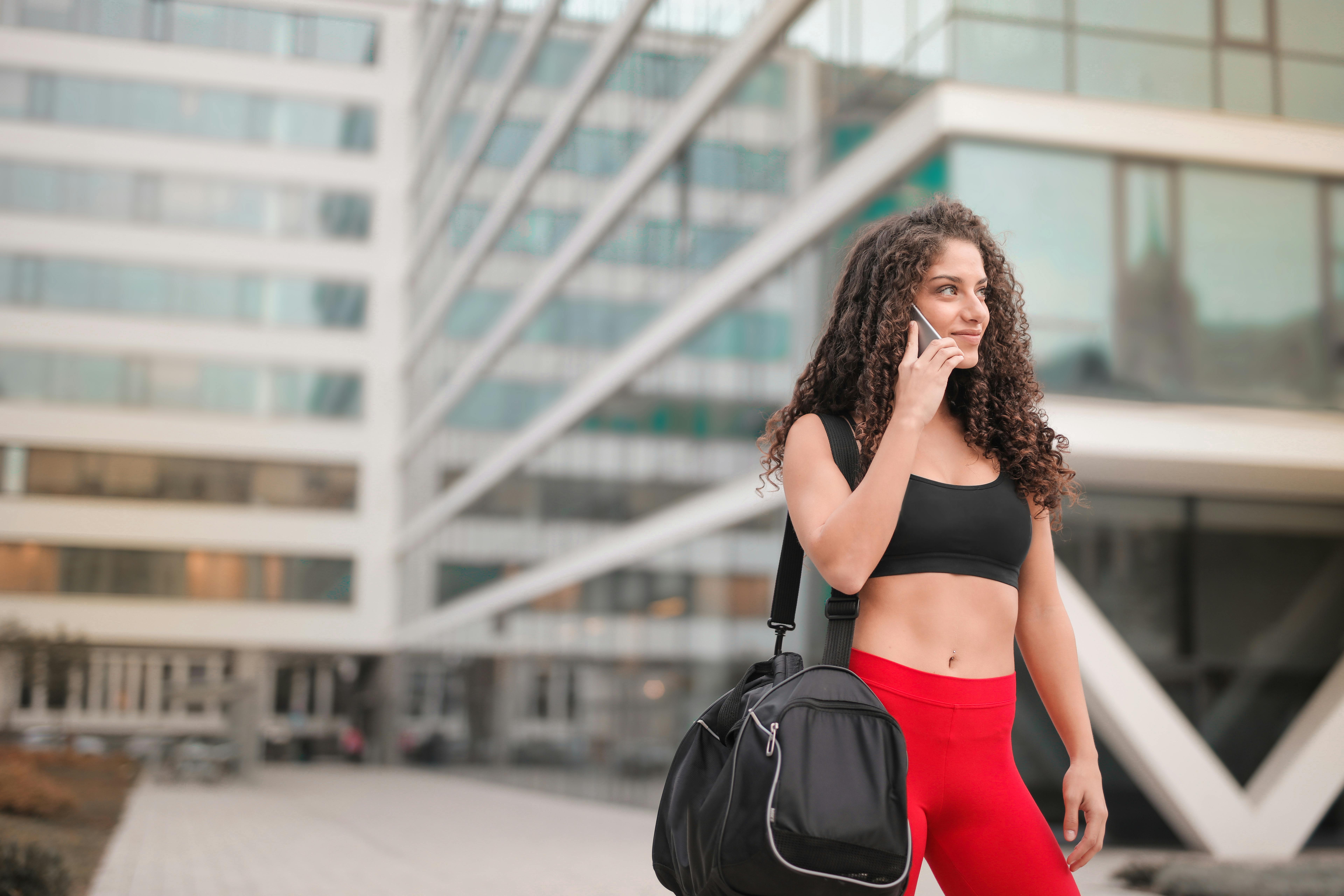 Eine Frau in Sportkleidung hält das Telefon dicht an ihr Ohr | Quelle: Pexels