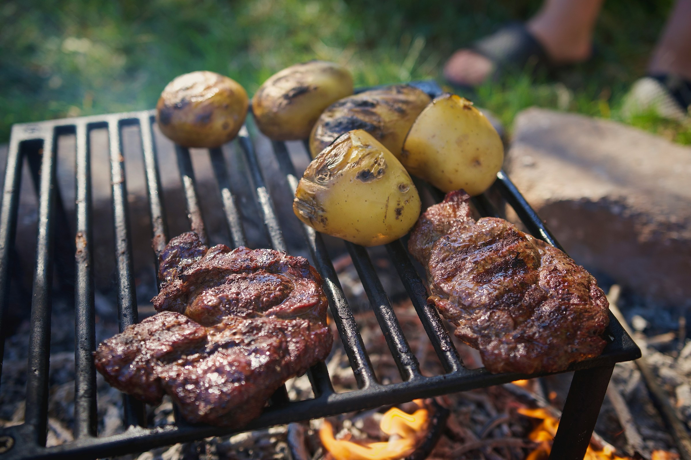 Fleisch und Kartoffeln auf einem Grill | Quelle: Unsplash