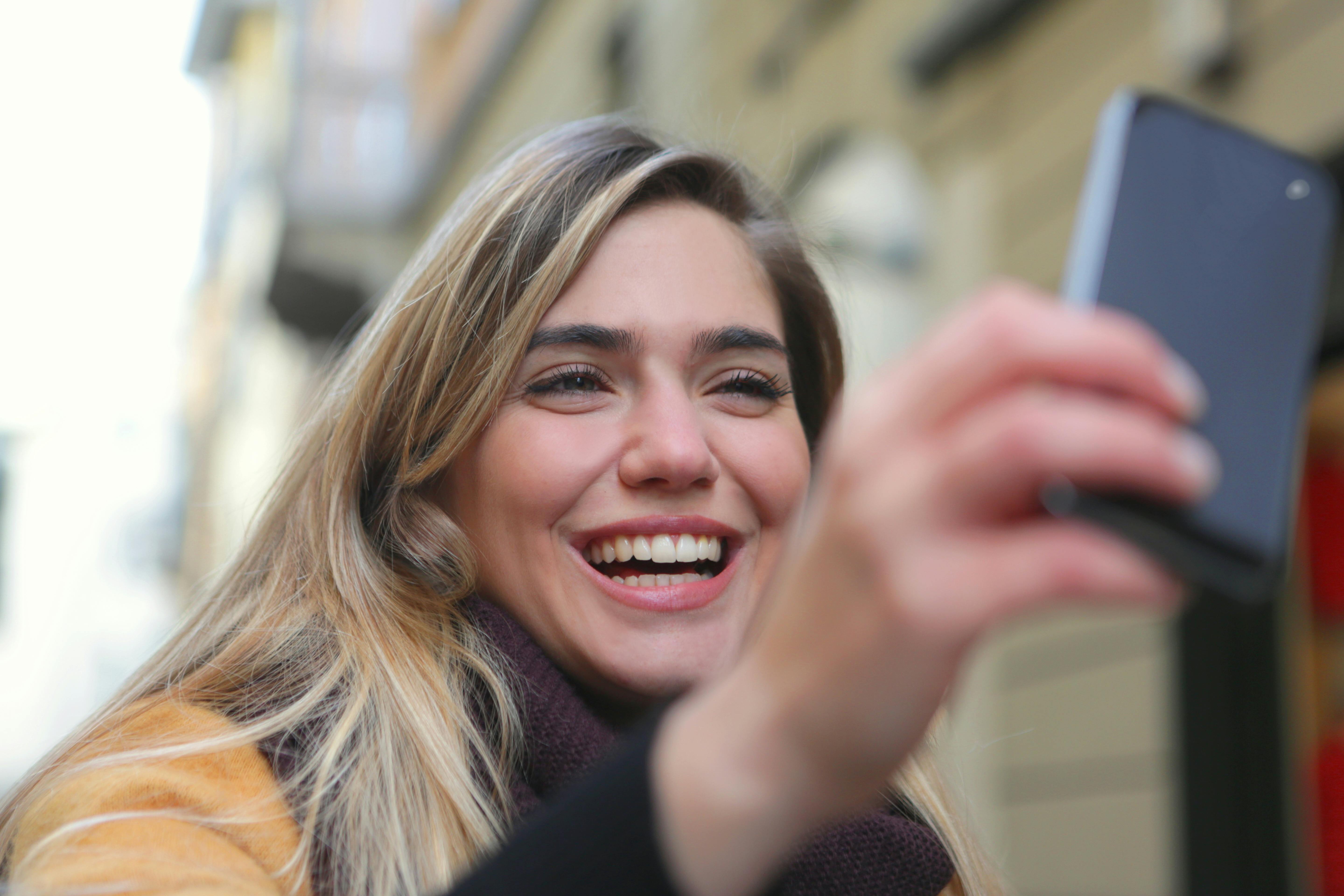 Eine Frau, die lacht, während sie auf ihr Telefon schaut | Quelle: Pexels