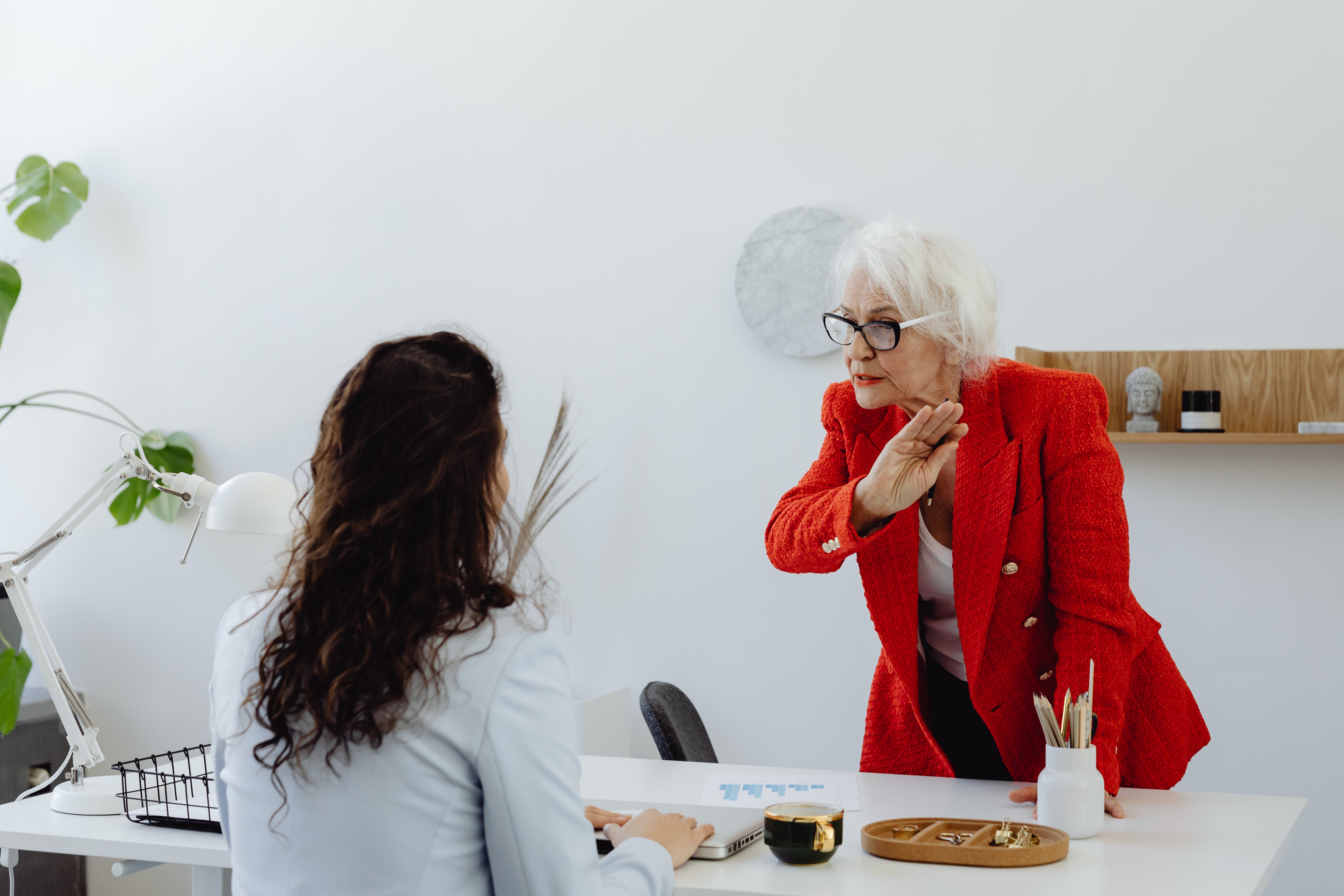Eine ältere Frau steht und streitet mit einer jüngeren, die sitzt | Quelle: Pexels