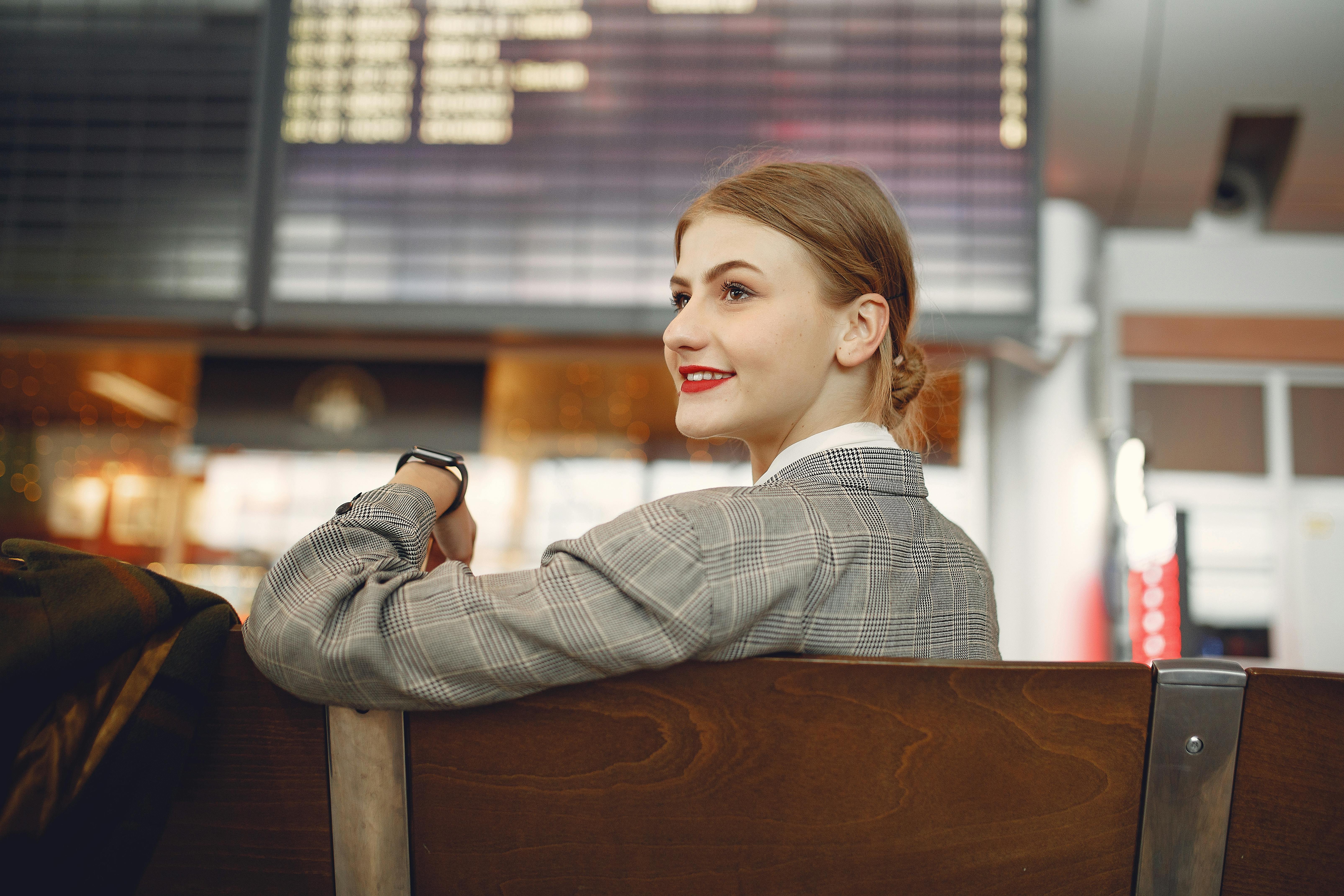 Eine glückliche Frau, die am Flughafen sitzt | Quelle: Pexels