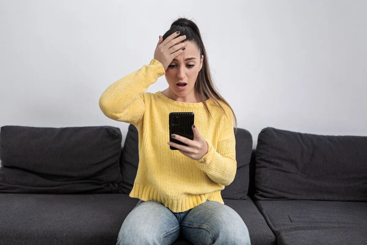 Eine Frau ist geschockt, während sie auf ihr Handy-Display schaut | Quelle: Getty Images