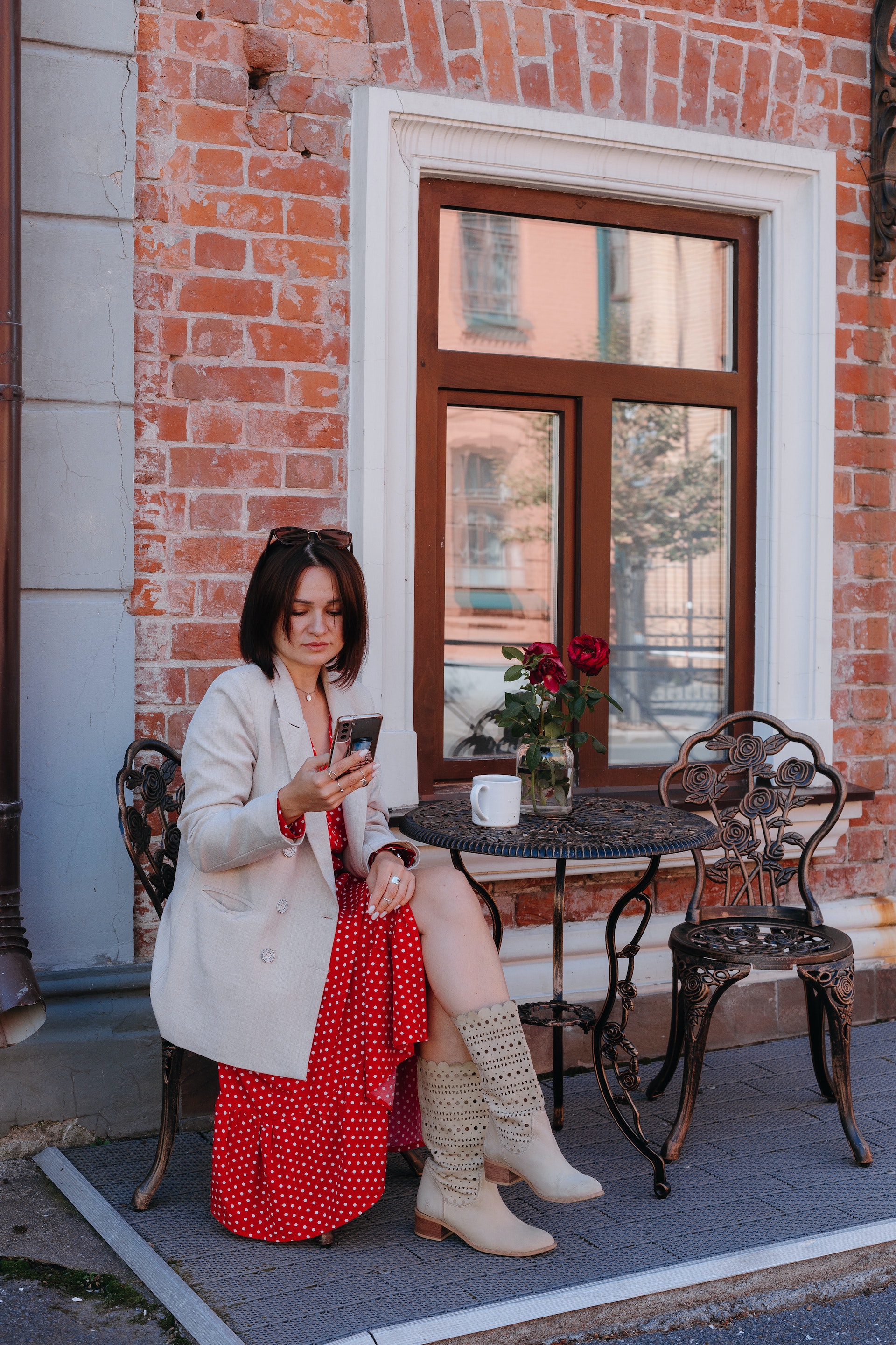 Eine Frau, die in einem Straßencafé sitzt und ihr Handy überprüft | Quelle: Pexels