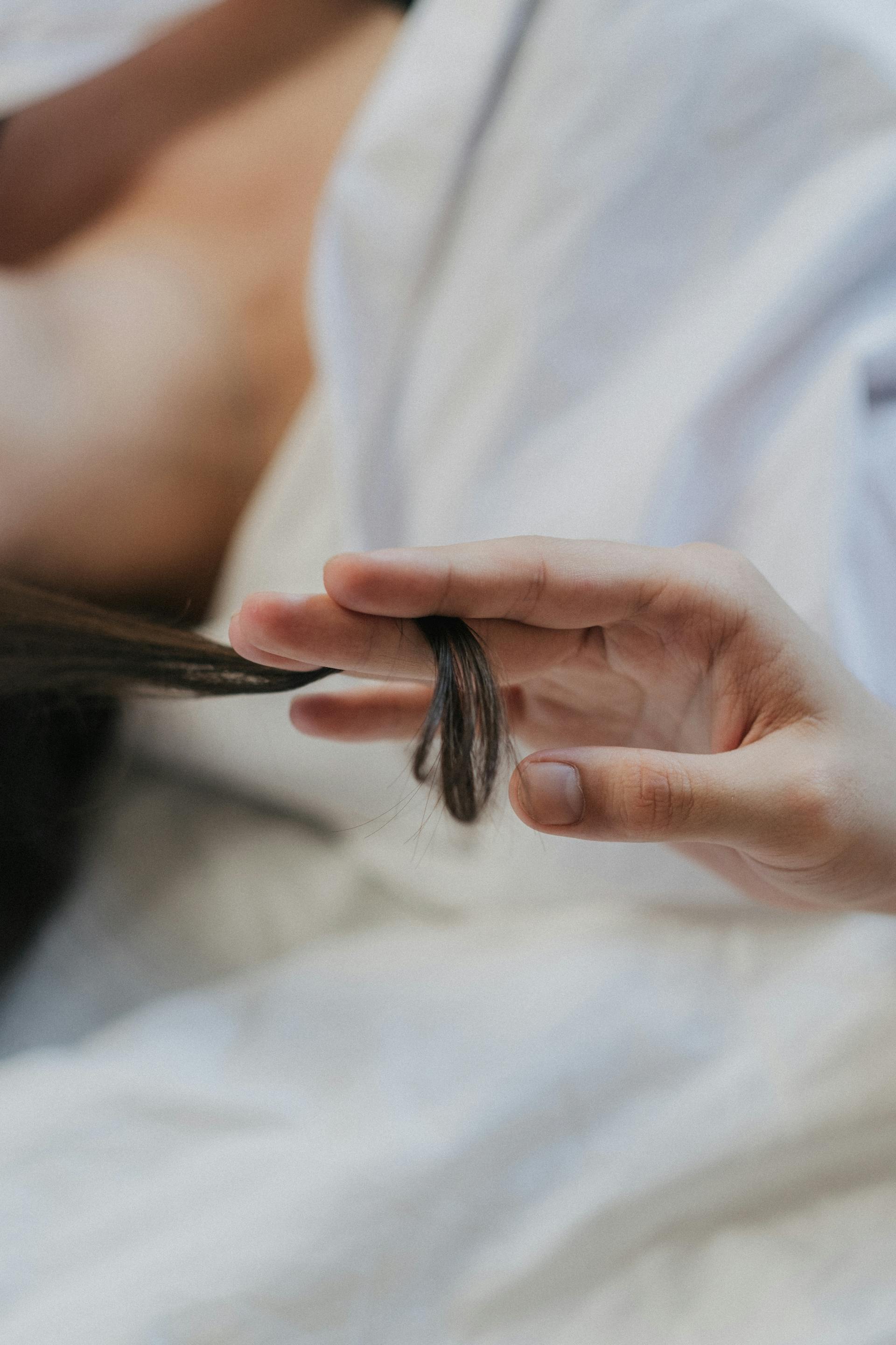 Eine Person zwirbelt eine Haarlocke | Quelle: Pexels