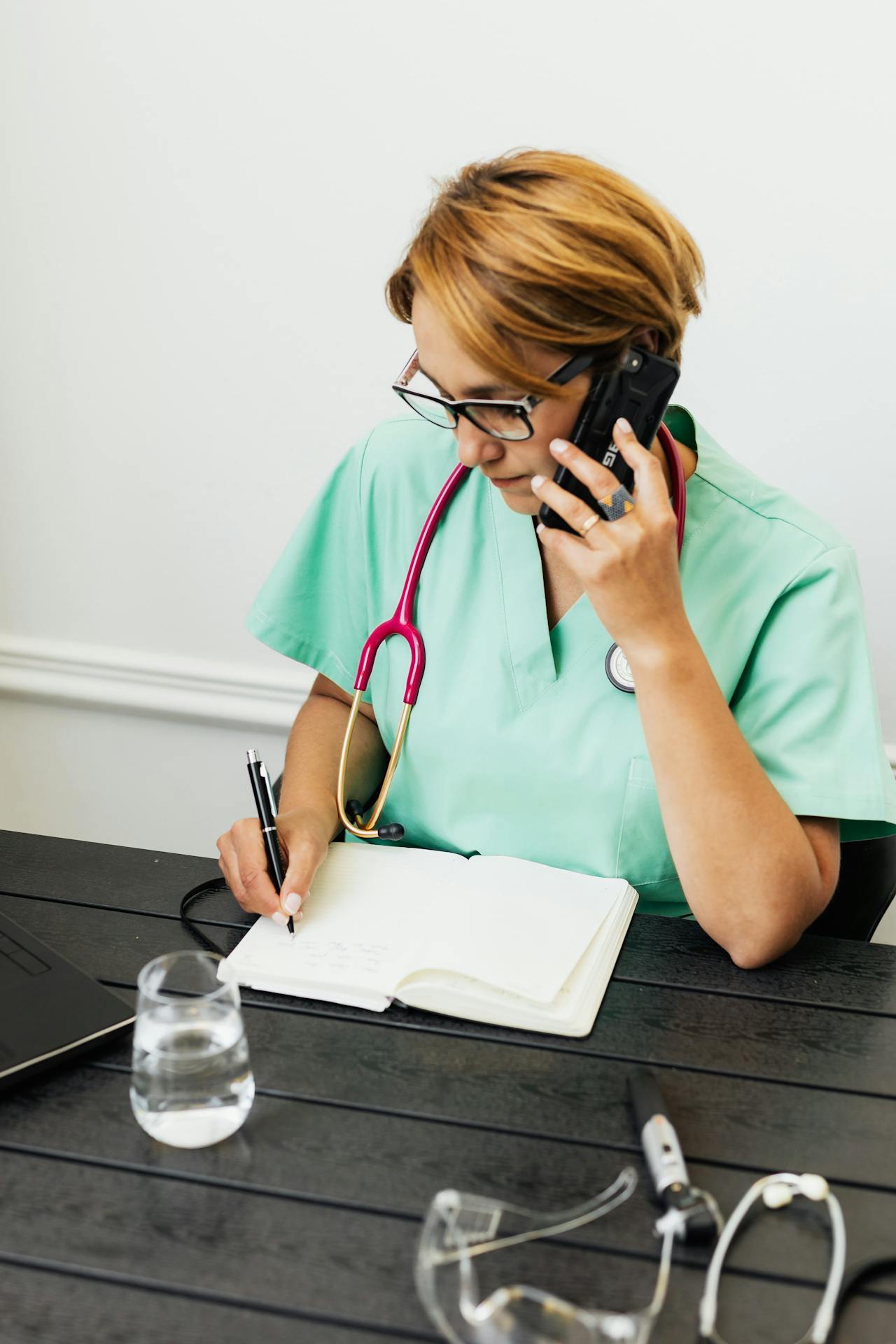 Medizinisches Personal telefoniert und schreibt in ein Notizbuch | Quelle: Pexels