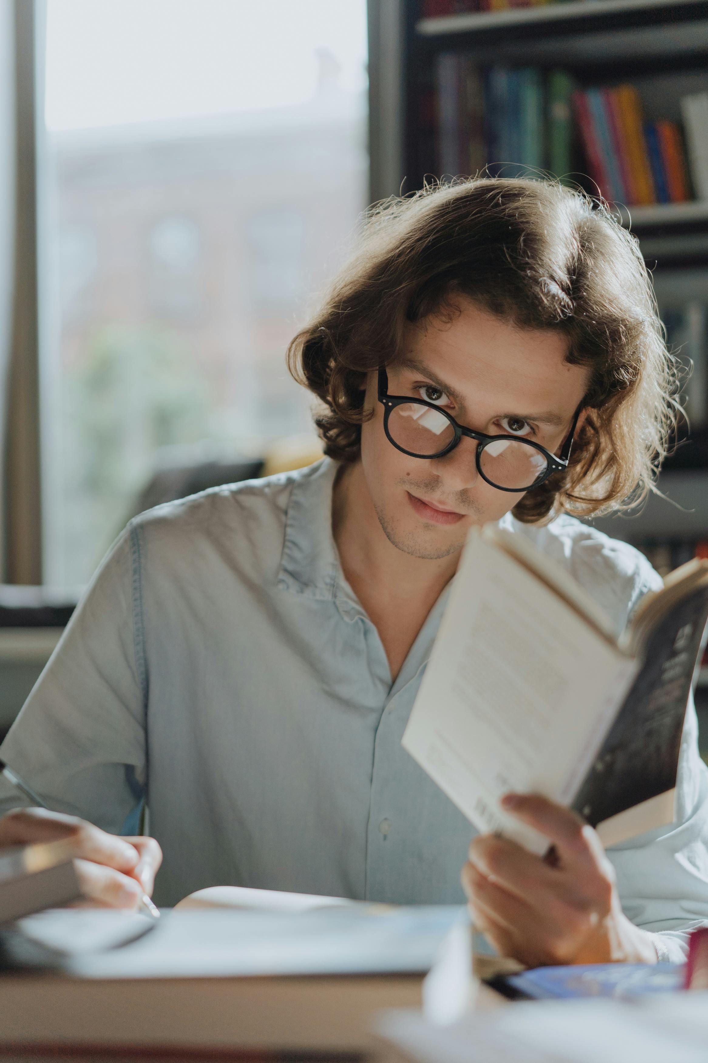 Ein Mann, der ein Buch liest und Notizen schreibt, während er jemanden ansieht | Quelle: Pexels