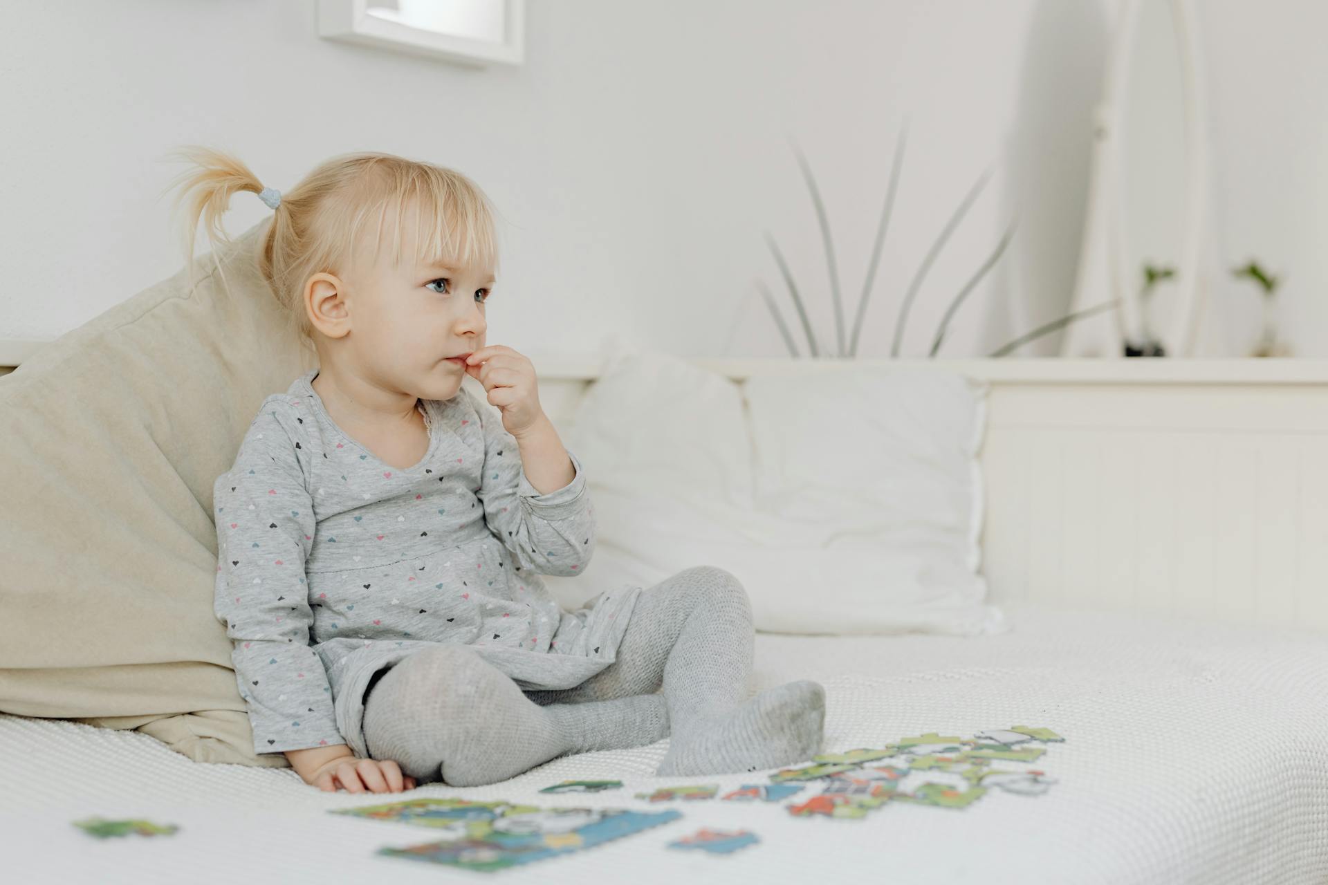 Ein kleines Mädchen sitzt allein und spielt mit einem Puzzle | Quelle: Pexels