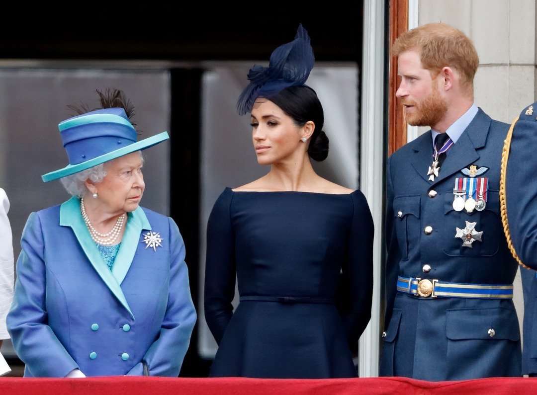 Königin Elizabeth II., Meghan und Prinz Harry beobachten am 10. Juli 2018 vom Balkon des Buckingham Palace in London, England, einen Vorbeiflug anlässlich des hundertjährigen Bestehens der Royal Air Force. | Quelle: Getty Images