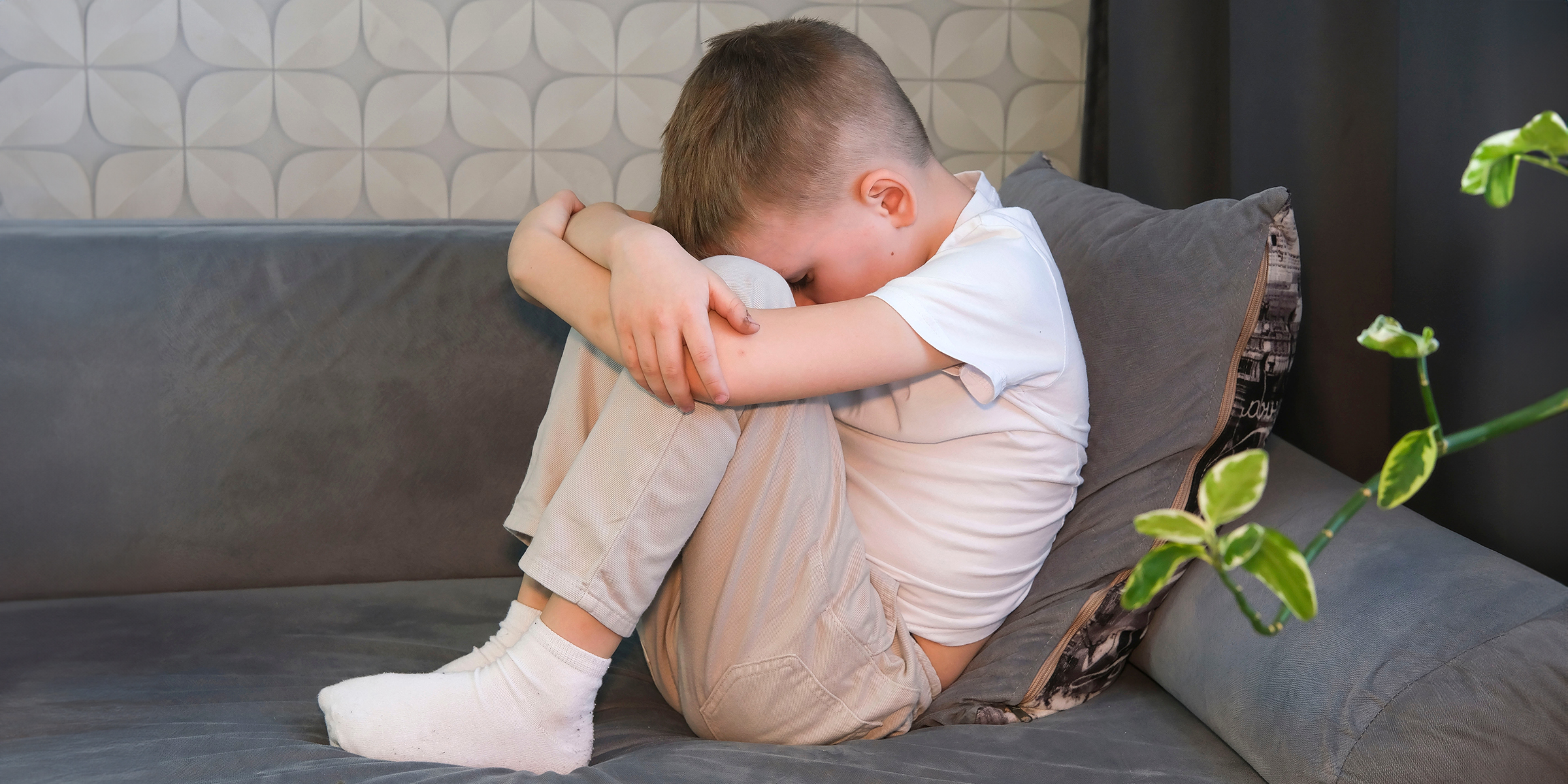 Ein aufgeregter kleiner Junge sitzt auf einer Couch | Quelle: Shutterstock