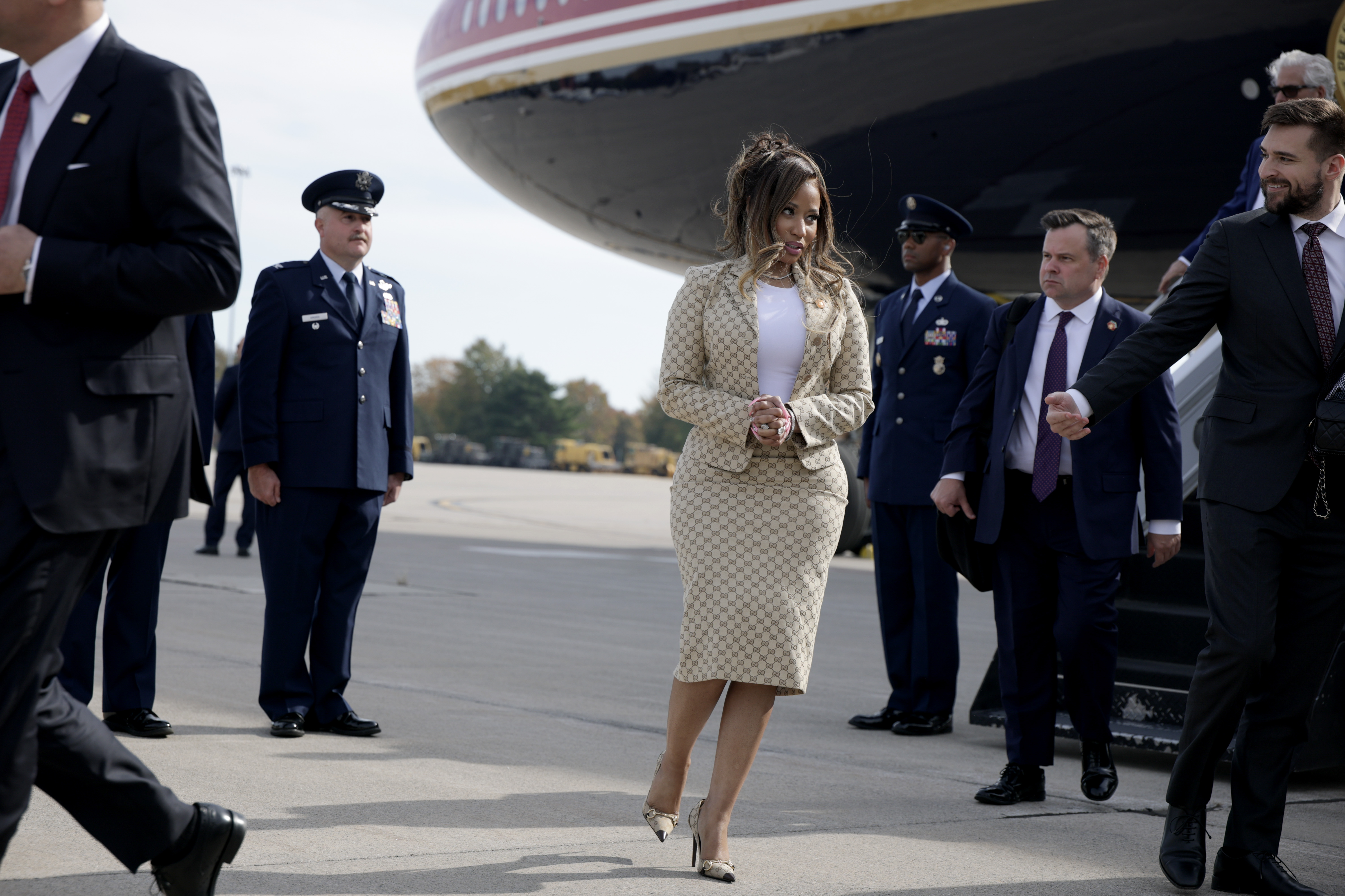 Nicki Minaj steht auf dem Rollfeld neben der Air Force One, umgeben von uniformierten Militärangehörigen und Sicherheitspersonal. Ihre metallischen Pumps mit spitzer Zehenpartie und der dazu passende Gucci-Rock runden den sorgfältig abgestimmten Look ab. | Quelle: Getty Images