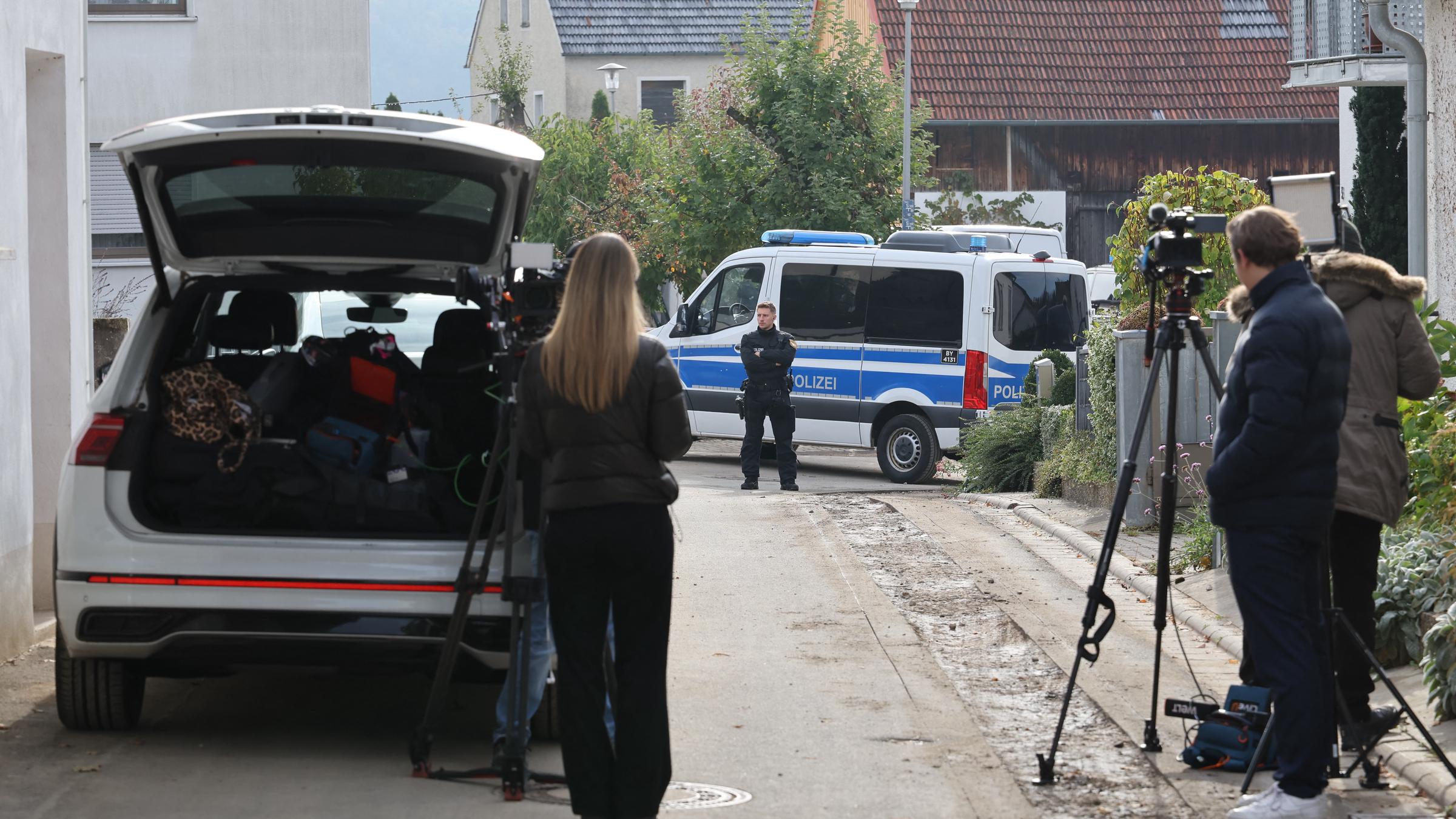 Vor einem Polizeifahrzeug in der Nähe des Tatorts stehen Kamerateams. | Quelle: Getty Images