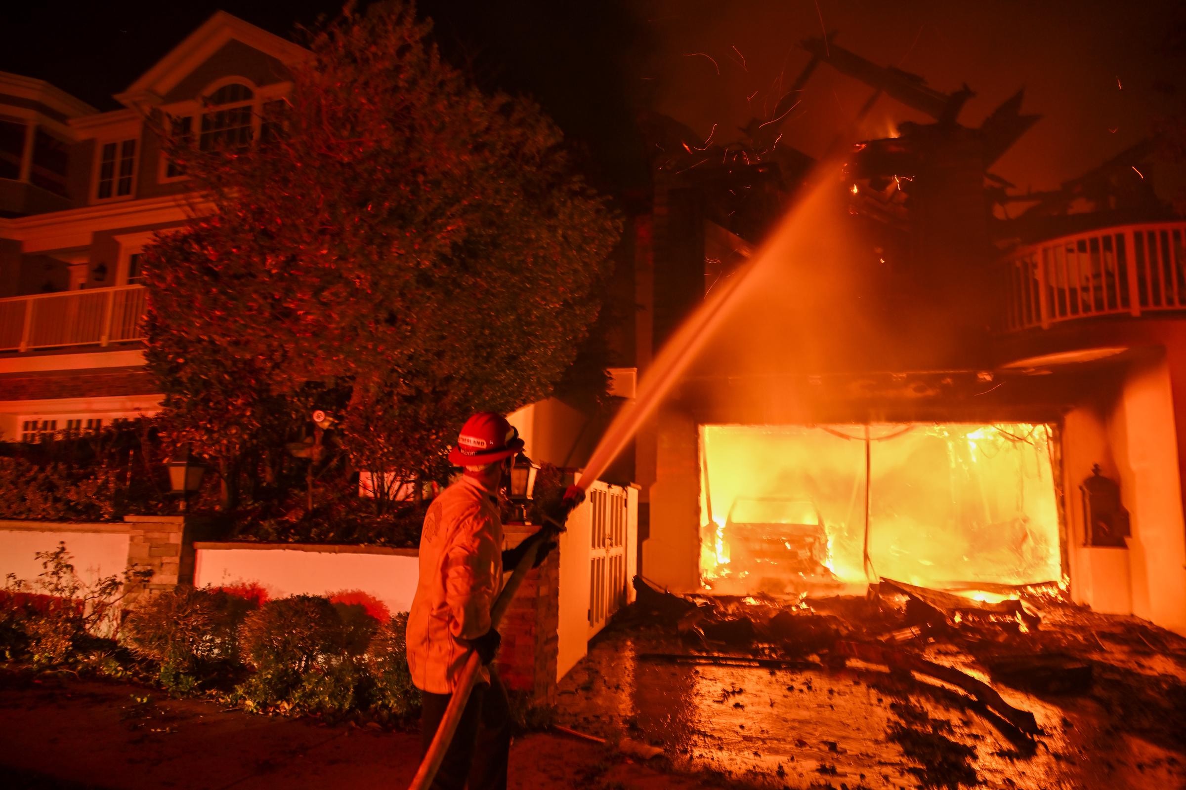 Ein Feuerwehrmann löscht ein in Brand geratenes Haus in Pacific Palisades, Kalifornien, am 8. Januar 2025. | Quelle: Getty Images