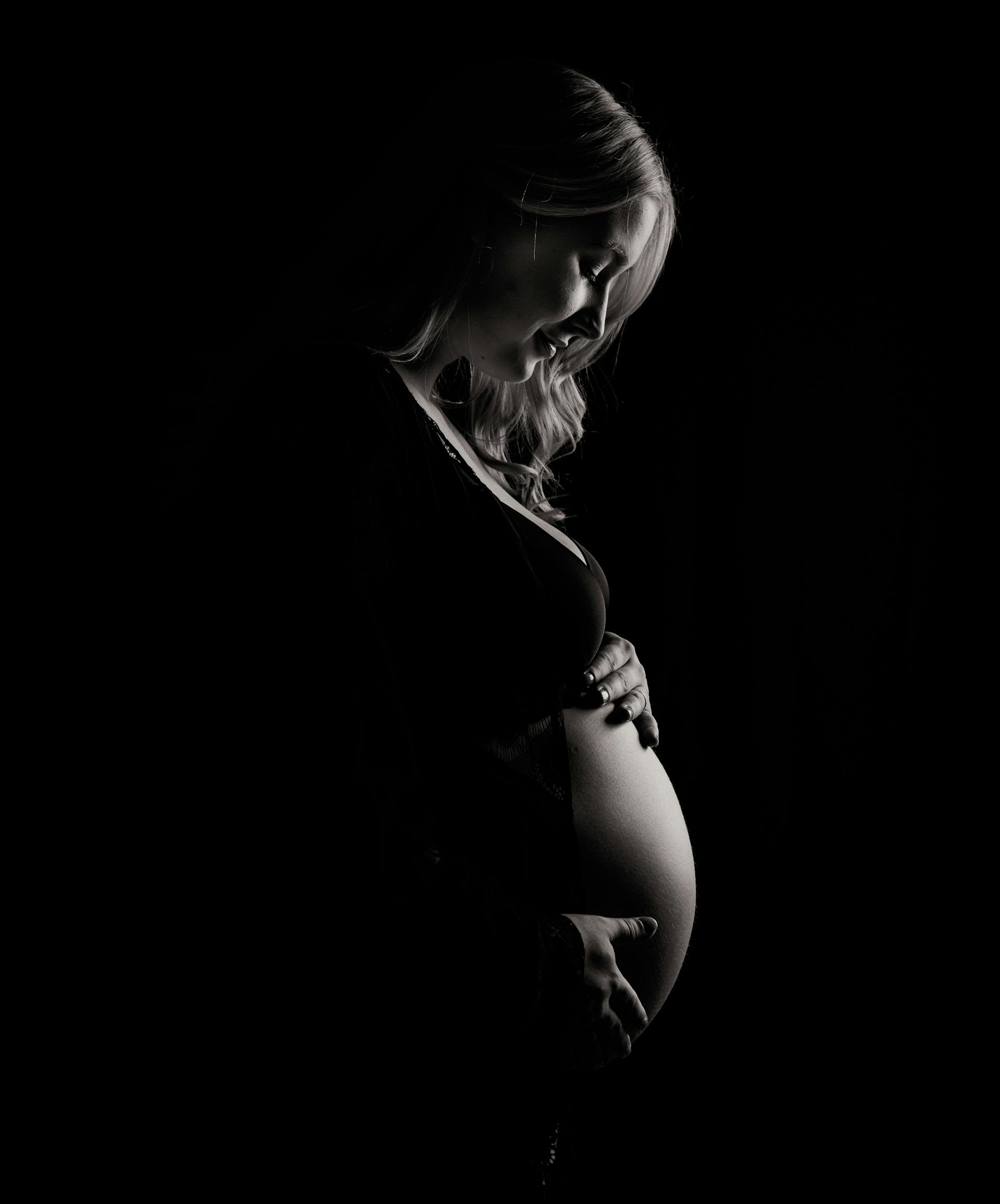 Ein Graustufenfoto einer schwangeren Frau, die ihren Babybauch hält | Quelle: Pexels