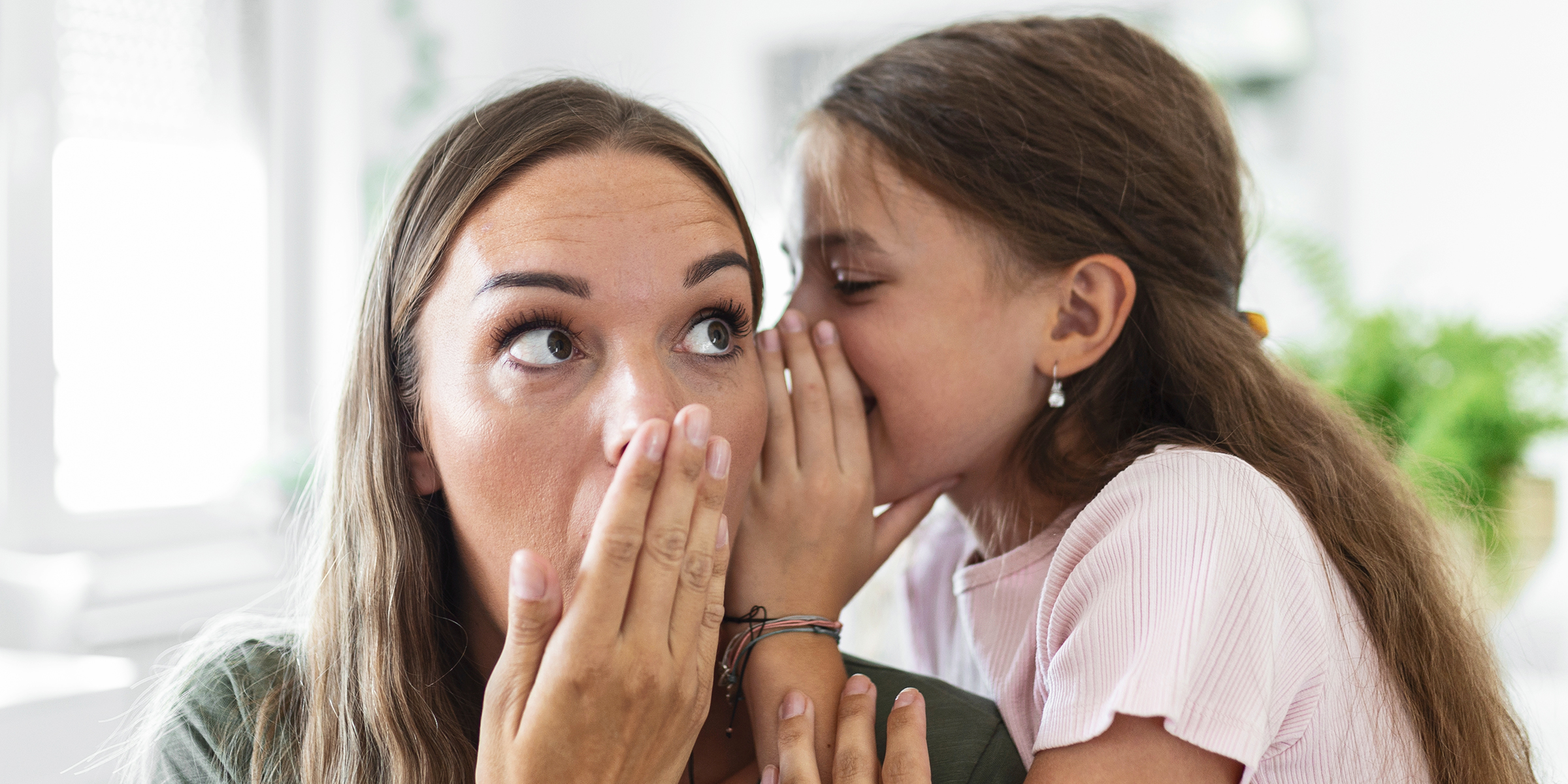 Ein Mädchen flüstert ihrer Mutter ins Ohr | Quelle: Shutterstock