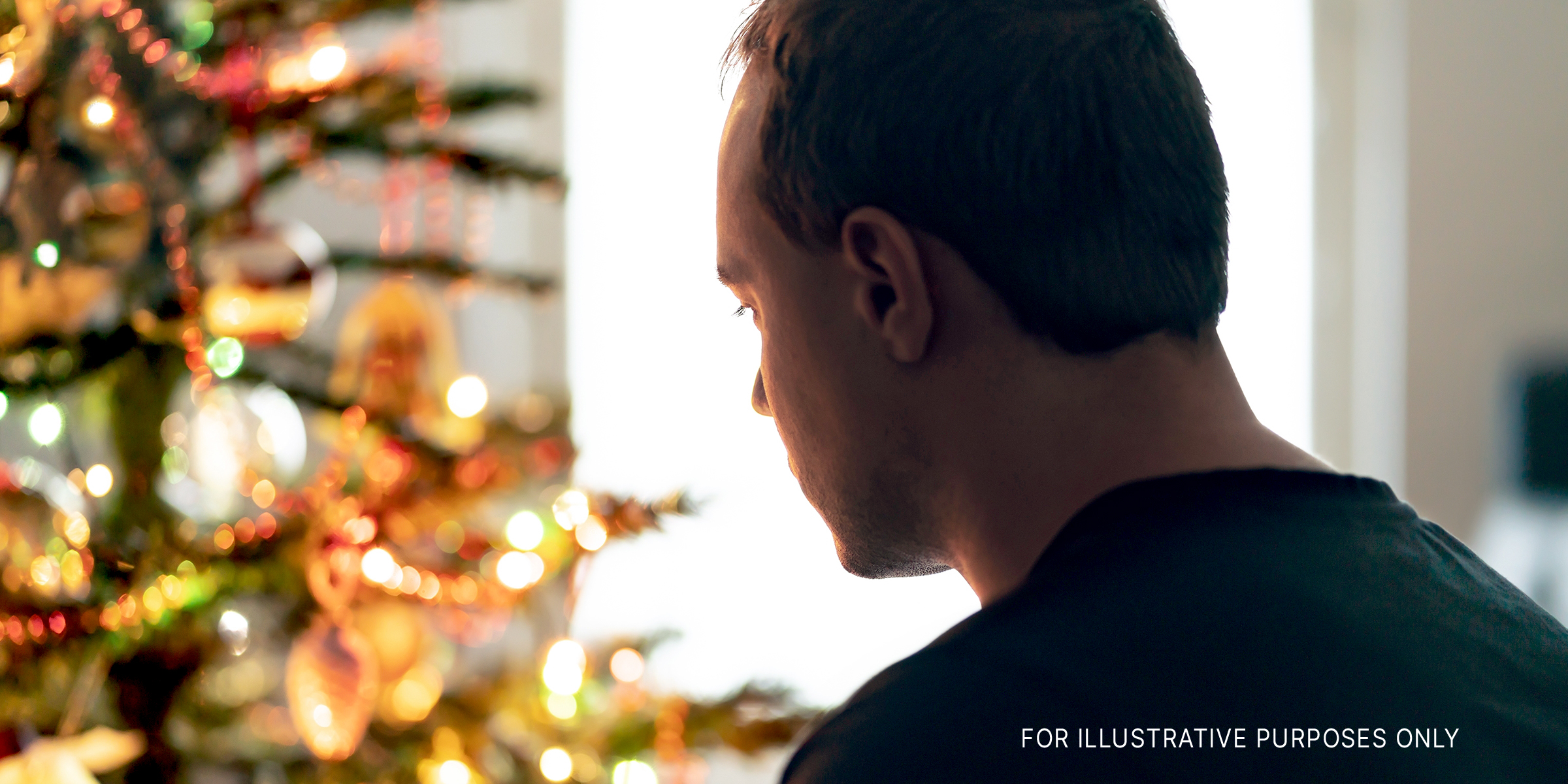 Mann starrt auf einen Weihnachtsbaum | Quelle: Shutterstock