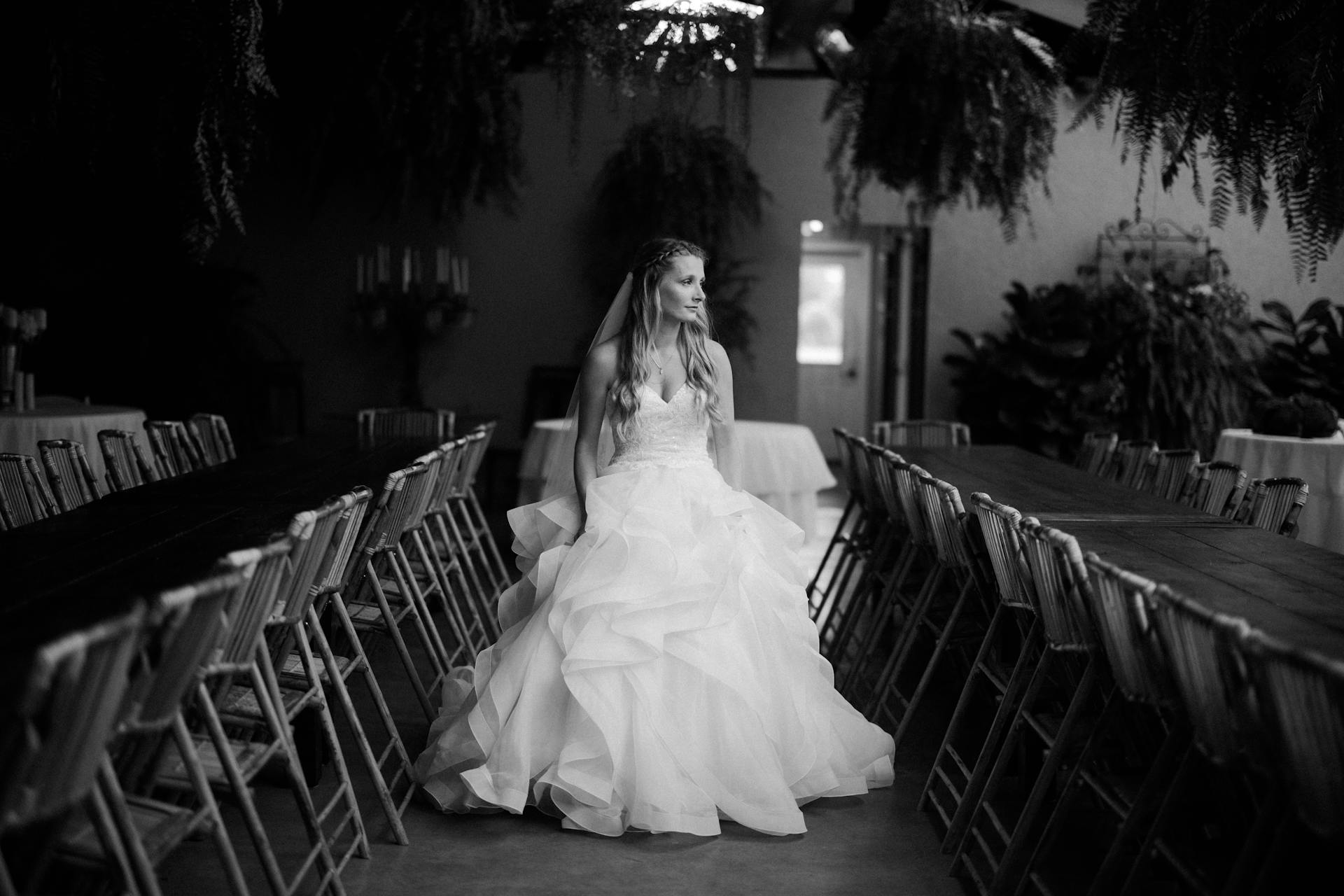 Ein Graustufenfoto einer Braut, die in einer Reihe leerer Stühle steht | Quelle: Pexels