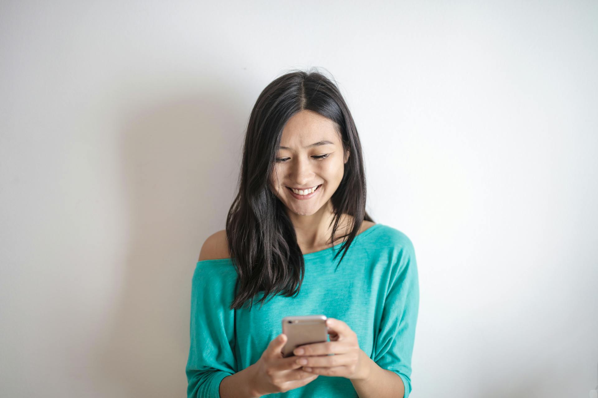 Eine Frau, die auf ihr Telefon lächelt | Quelle: Pexels