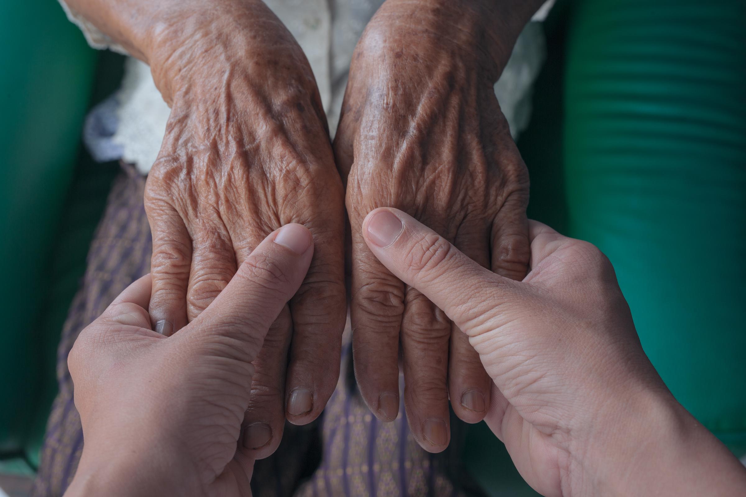 Nahaufnahme eines jungen Mannes, der die Hand seiner Großmutter hält | Quelle: Freepik