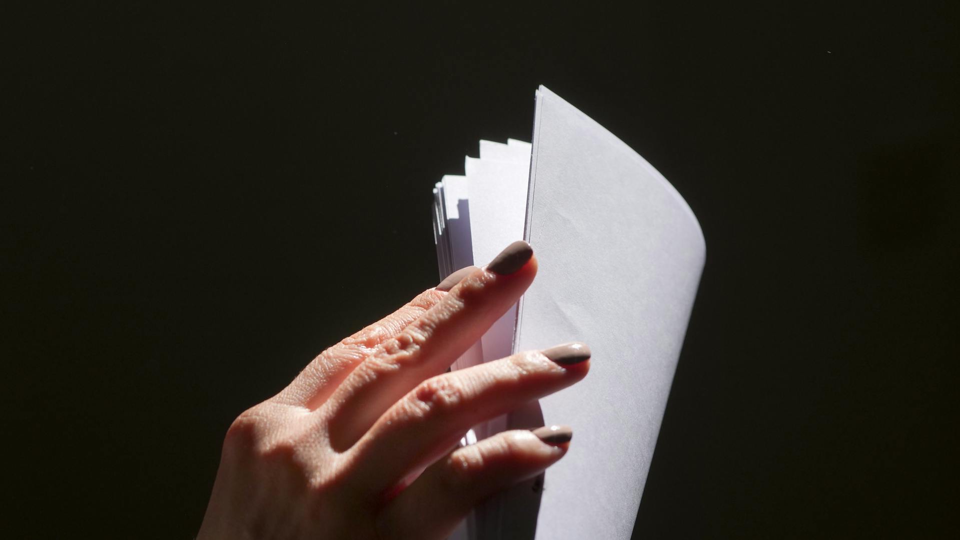 Nahaufnahme einer Frau, die ein Blatt Papier durchblättert | Quelle: Pexels