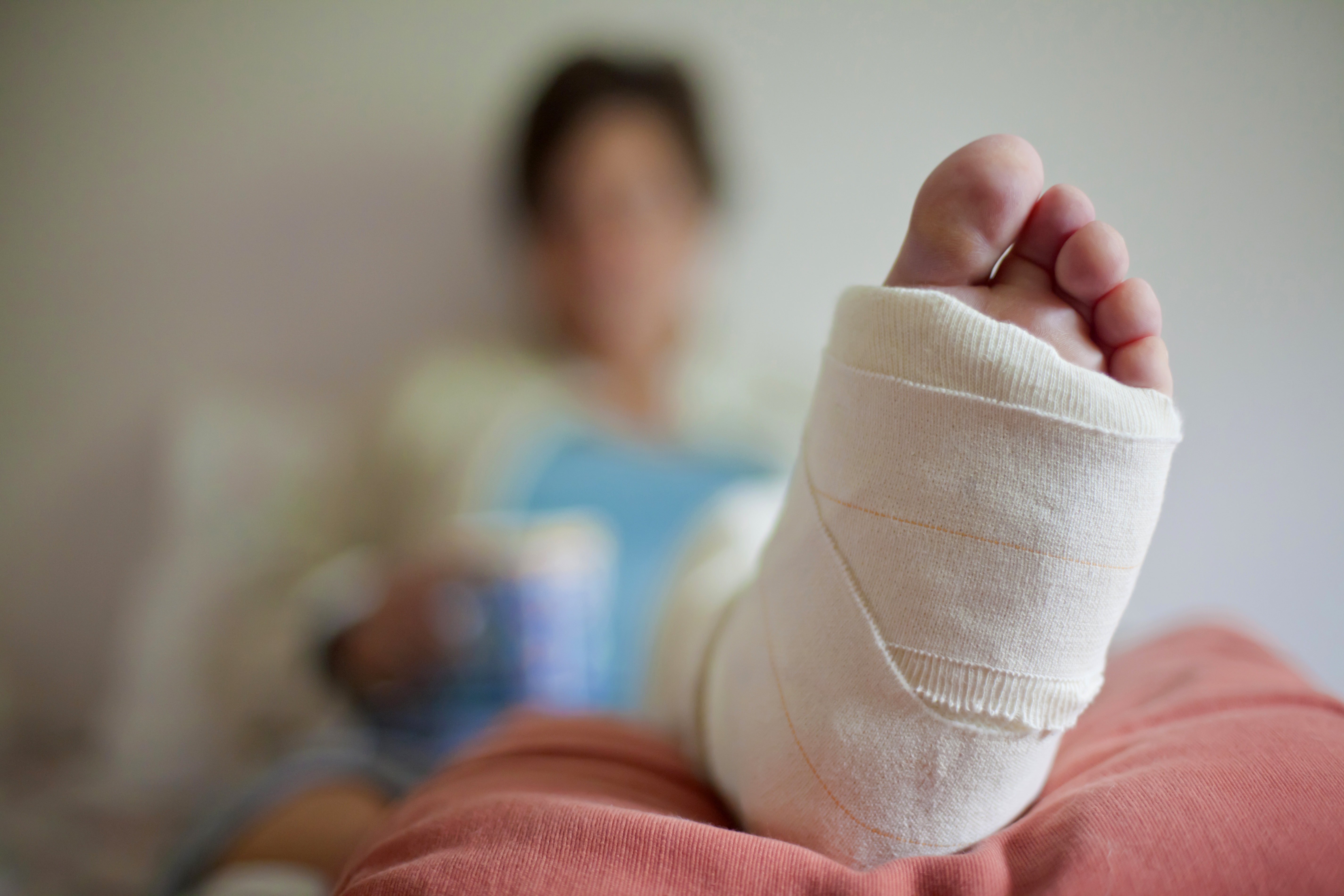 Frau mit gebrochenem Bein auf einem Bett liegend | Quelle: Getty Images