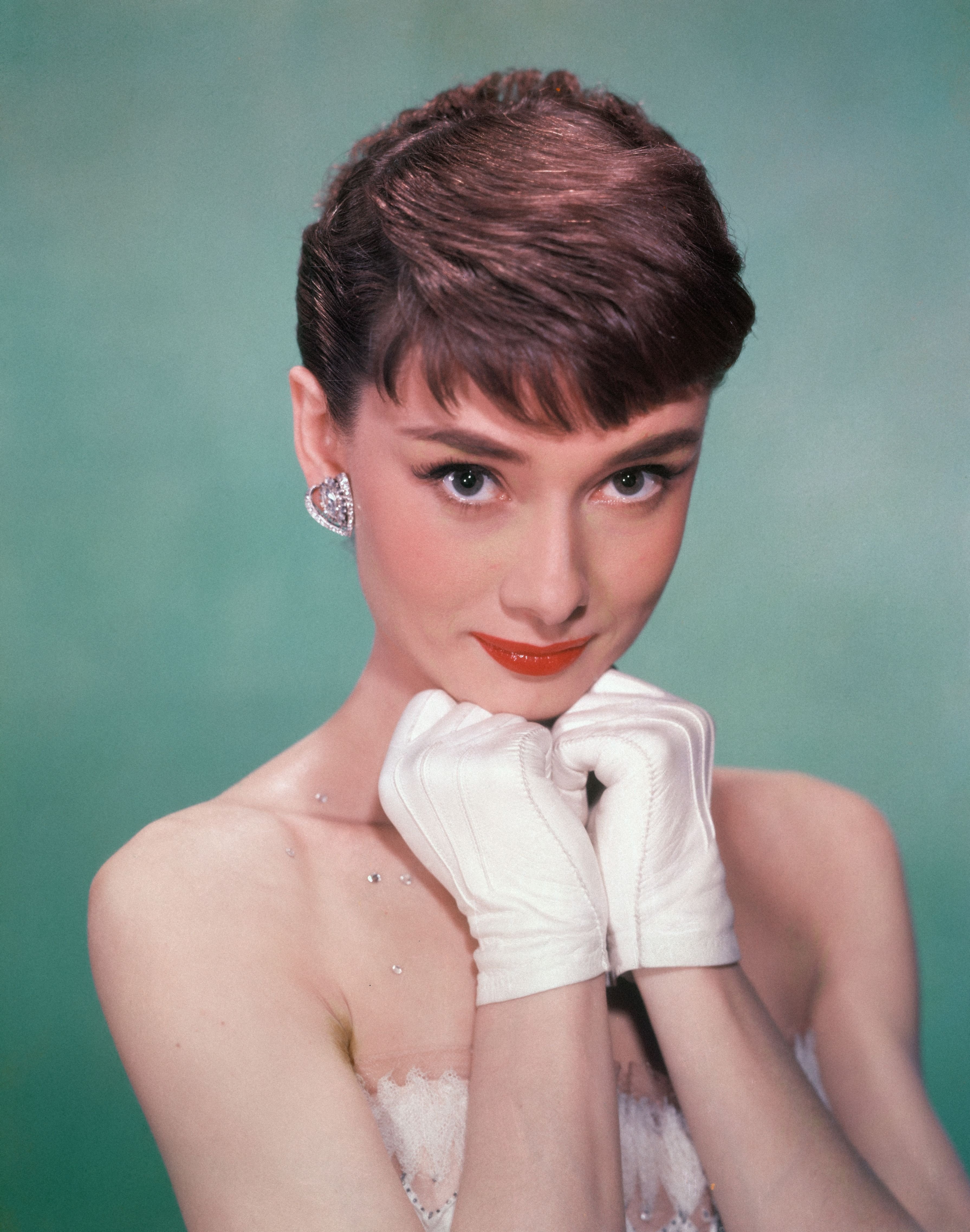 Porträt der in Belgien geborenen amerikanischen Schauspielerin Audrey Hepburn (1929 - 1993), die ein trägerloses Kleid trägt und weiße Kinderhandschuhe bis zum Kinn hält, Anfang der 1950er Jahre. (Foto von Hulton Archive) I Quelle: Getty Images