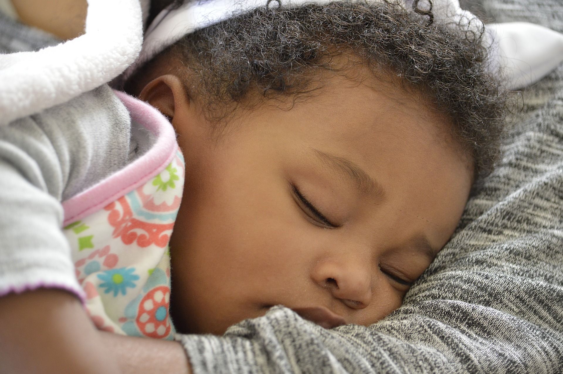 Ein Baby schläft friedlich auf einer grauen Decke. | Quelle: Shutterstock