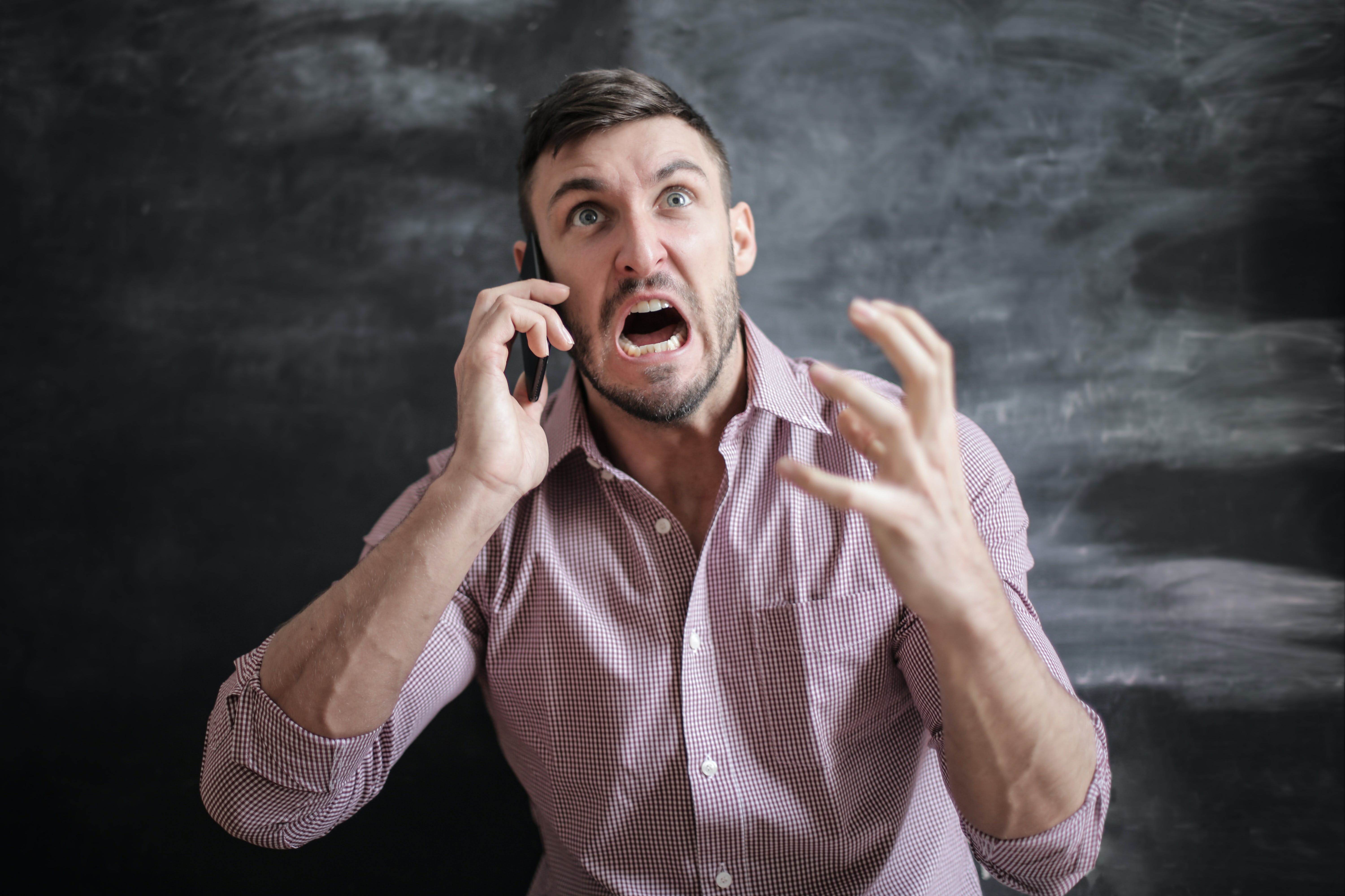 Ein Mann schreit und gestikuliert wütend während eines Telefonats | Quelle: Pexels