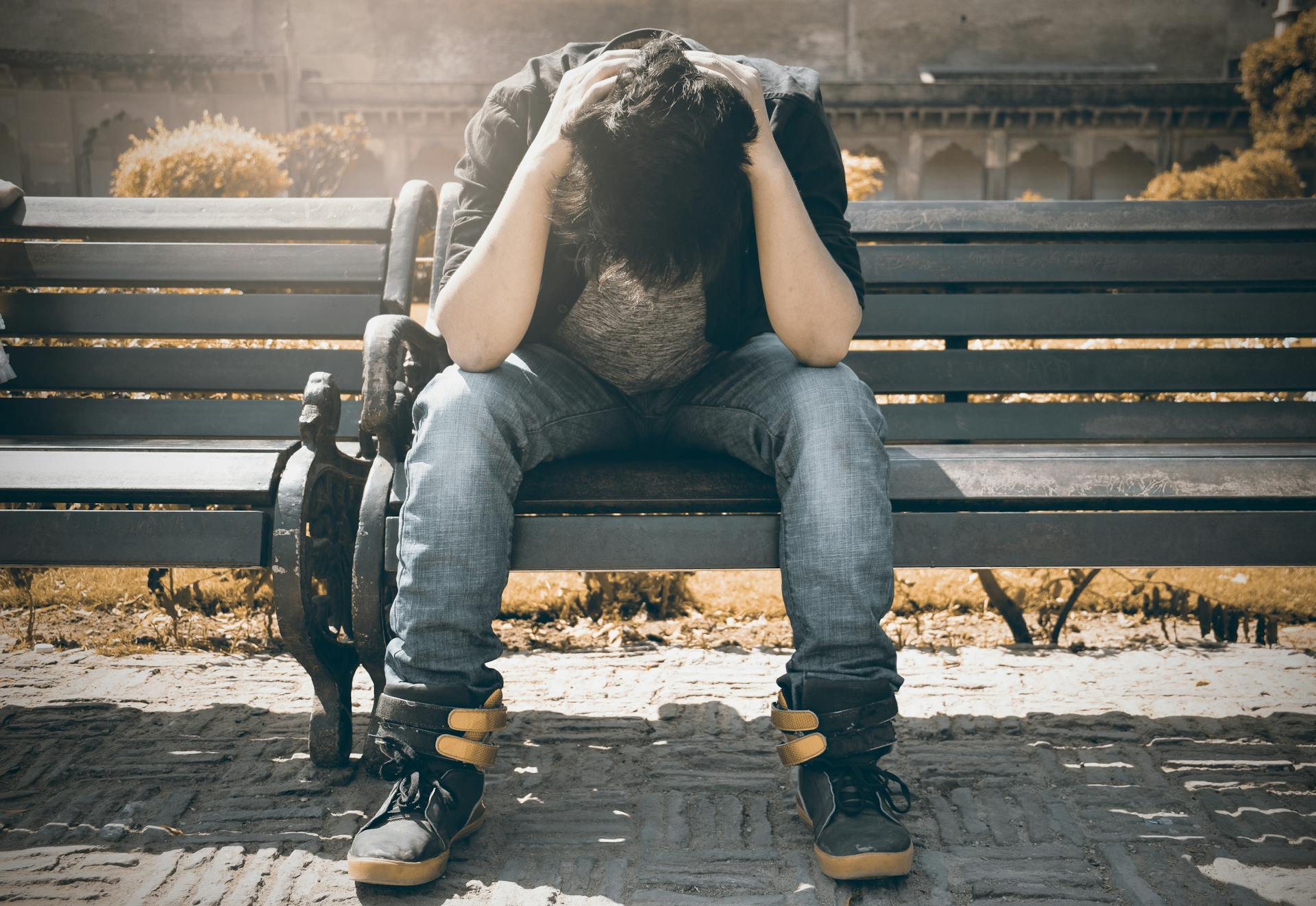 A stressed young man sits on a bench | Source: Pexels