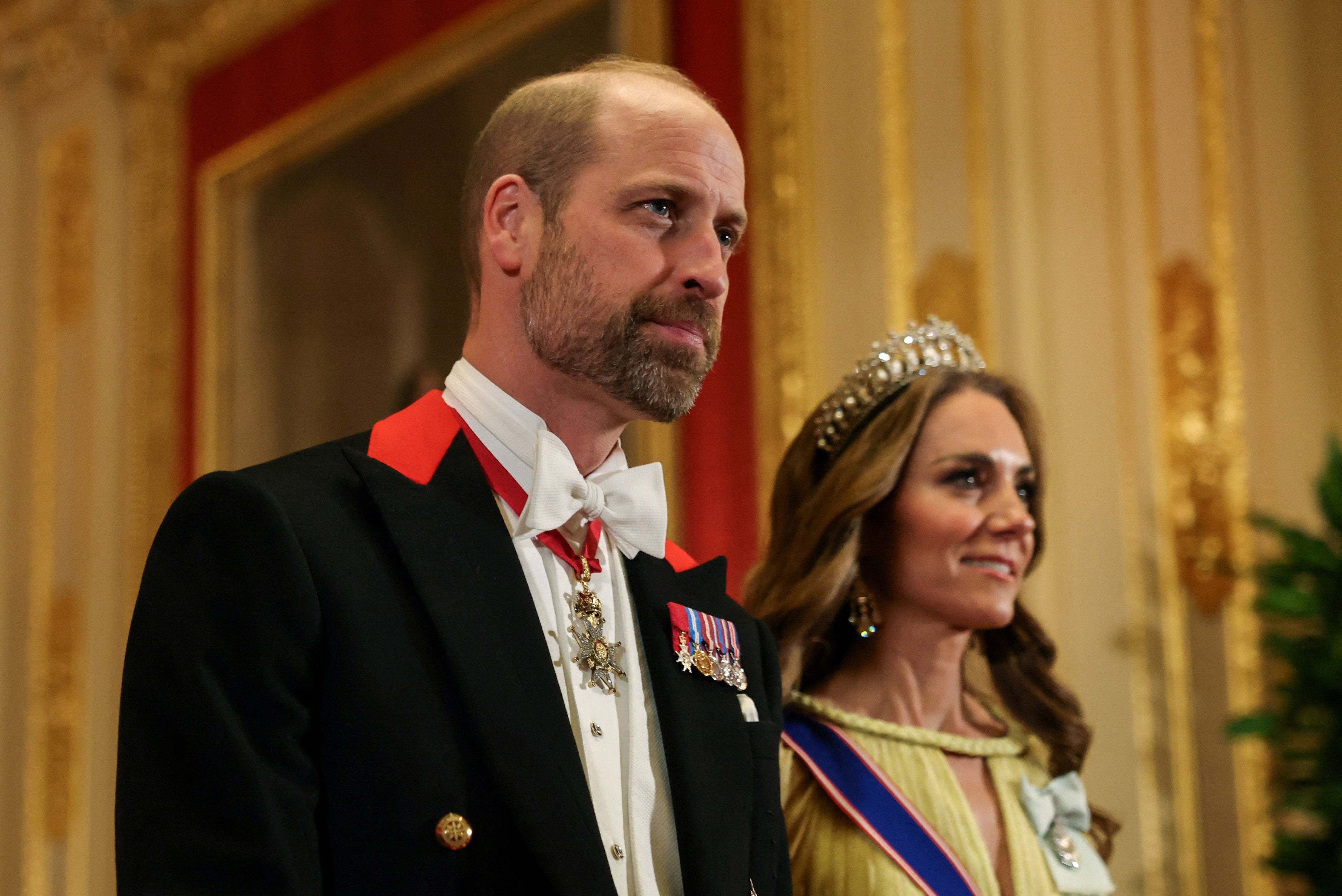 Prinz William zeigt neben Catherine, der Prinzessin von Wales, bei ihrem abendlichen Auftritt im Windsor Castle am 20. Oktober 2026 einen auffälligen Bartschatten. Der zukünftige König kombiniert seinen gepflegten Bart mit einem traditionellen schwarzen Windsor-Frack mit leuchtend roten Reversakzenten, einer weißen Krawatte und kleinen Medaillen, während Catherine in ihrer Tiara und einem pastellgelben Abendkleid danebensteht. | Quelle: Getty Images