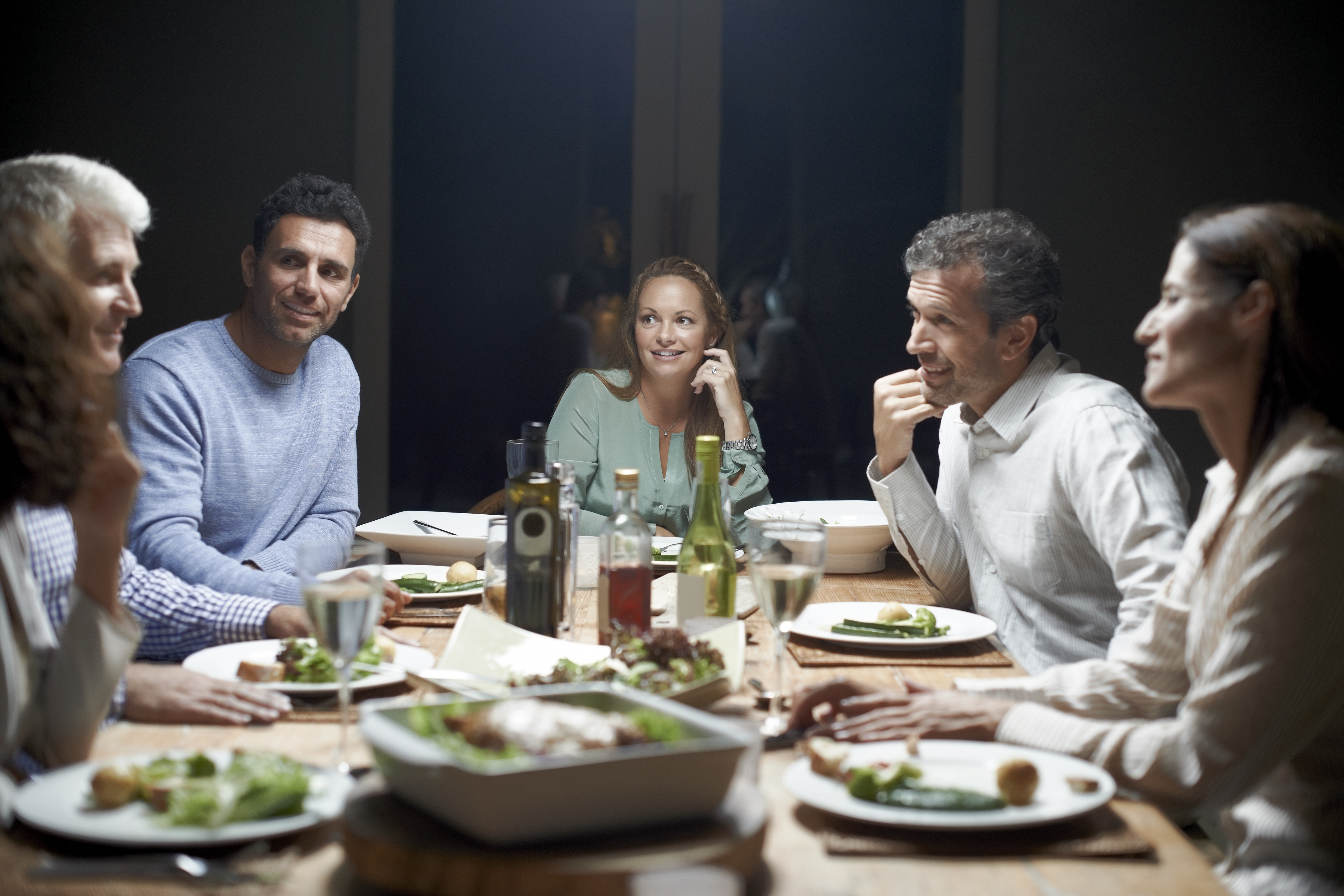Freunde unterhalten sich beim Abendessen am Tisch | Quelle: Getty Images