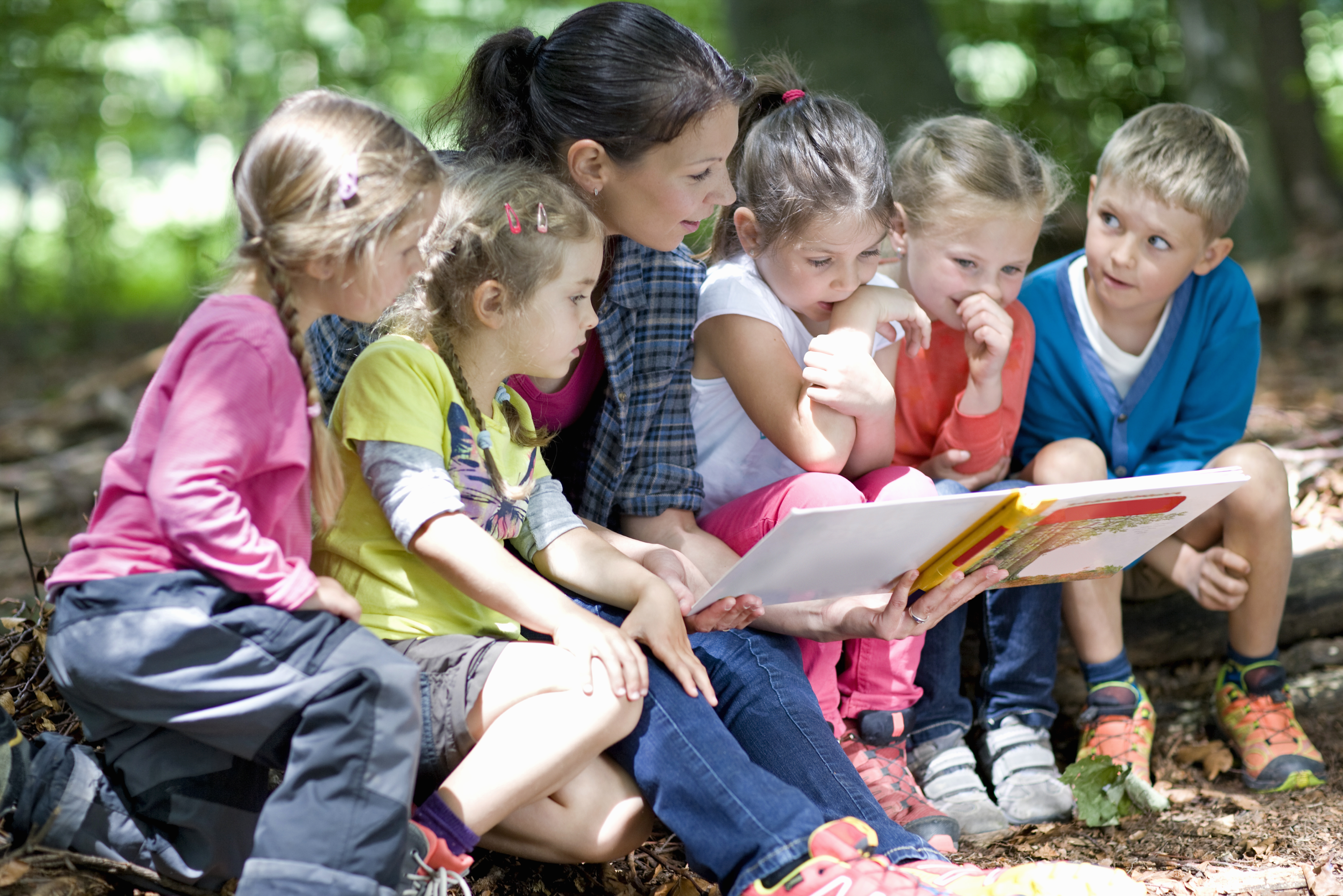 Frau liest kleinen Kindern ein Buch vor | Quelle: Shutterstock