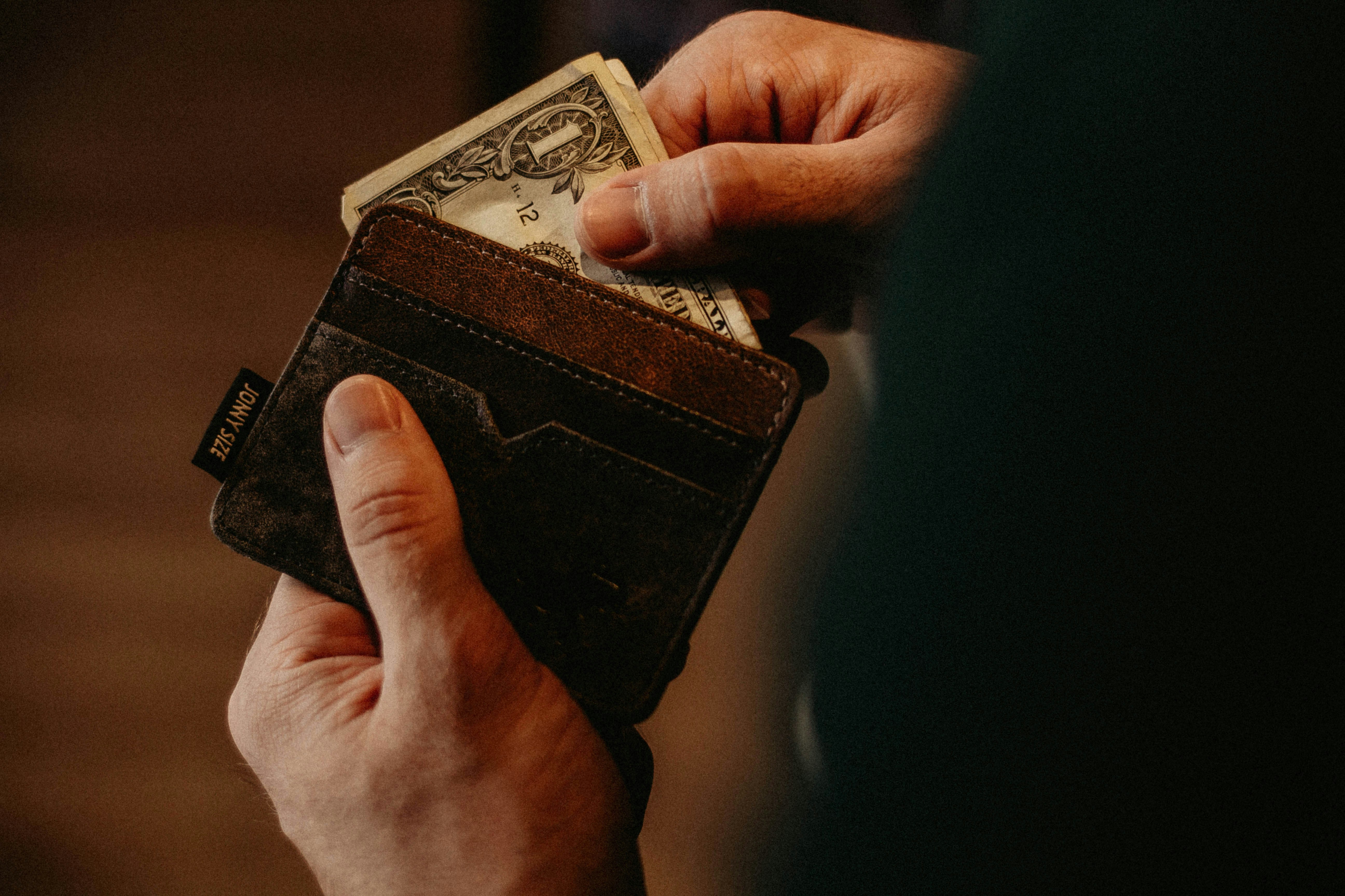 Eine Person, die Bargeld aus ihrem Portemonnaie zieht | Quelle: Unsplash