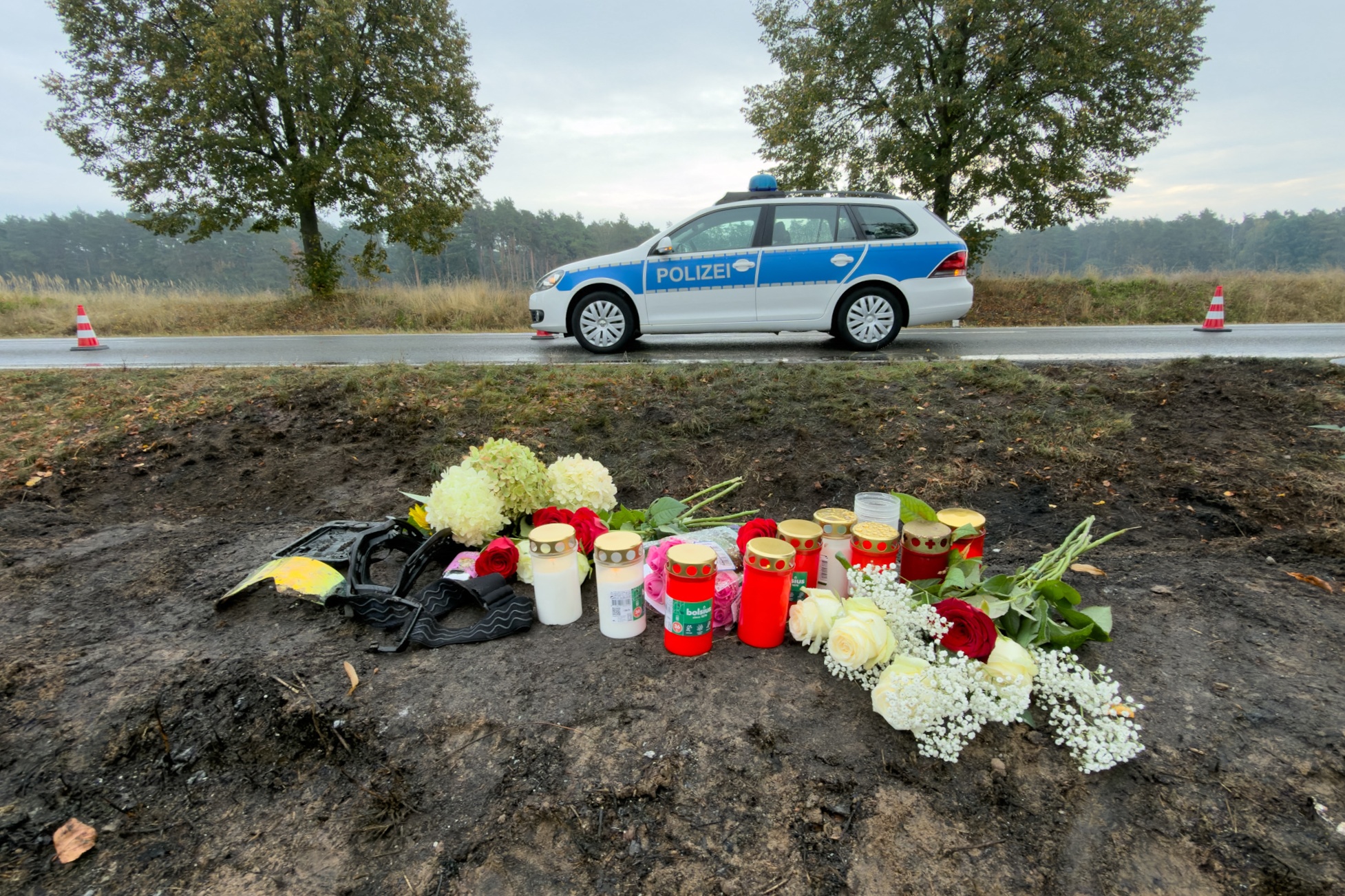Am Straßenrand liegen Blumen zum Gedenken an die Opfer des Verkehrsunfalls, während ein Polizeistreifenwagen am Unfallort geparkt ist. | Quelle: Getty Images