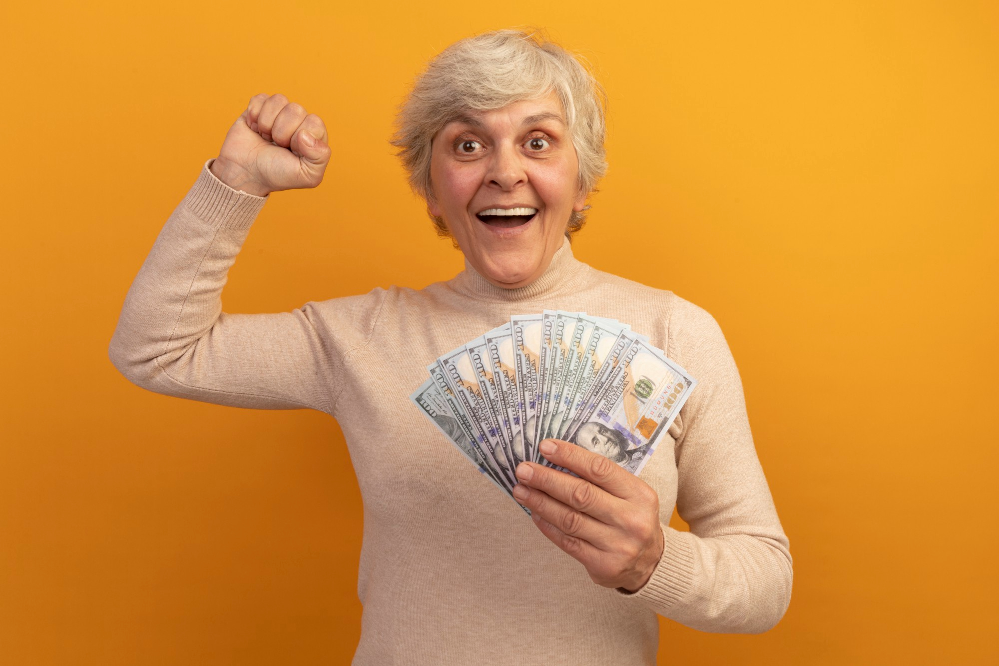 Eine Frau mittleren Alters feiert, während sie Geld in einer Hand hält | Quelle: Freepik