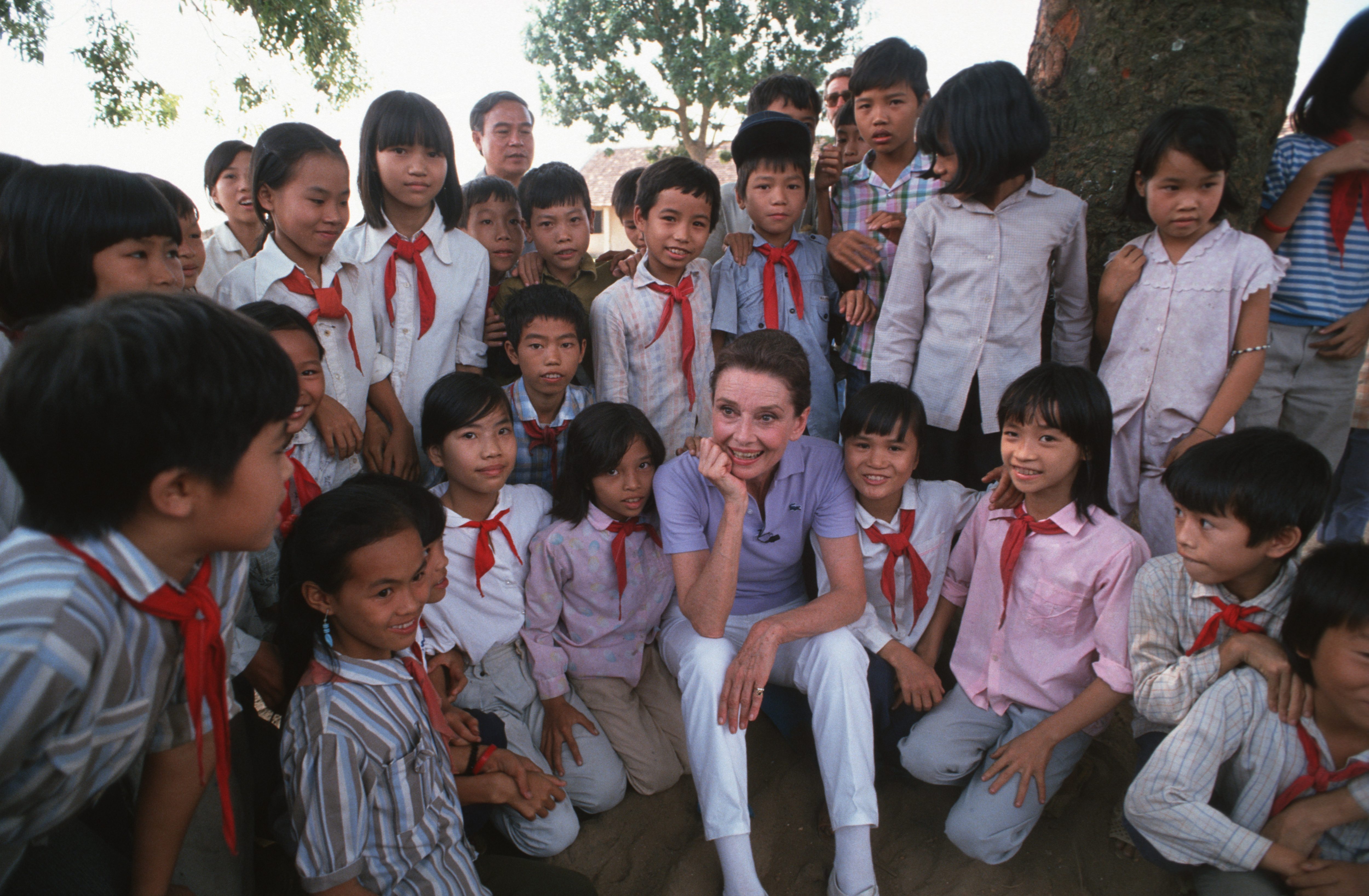 Audrey Hepburn nimmt sich am 1. Oktober 1990 in einem kleinen Dorf in der Nähe von Hanoi Zeit, um einige Schulkinder in Uniform kennenzulernen | Quelle: Getty Images