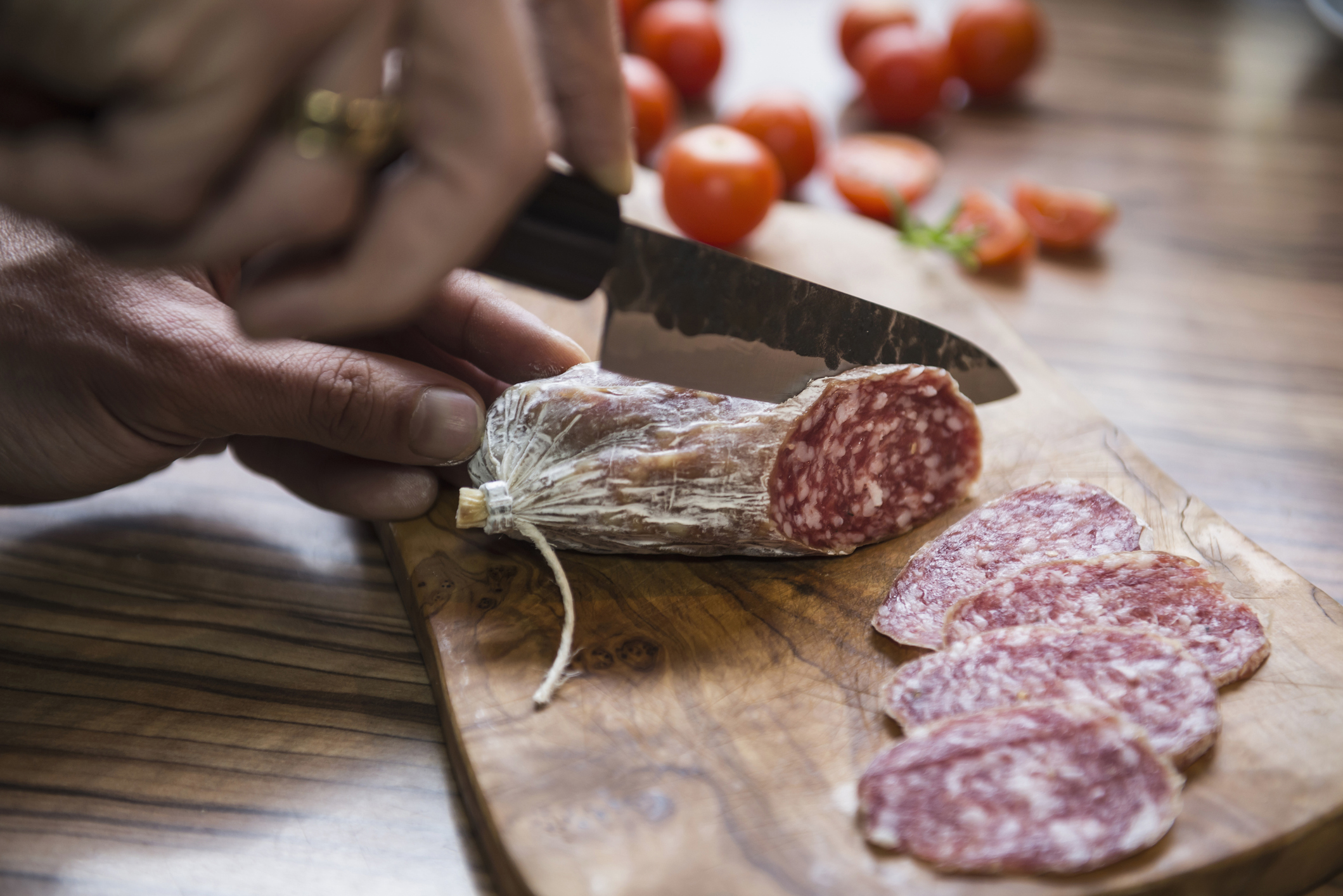 Eine Hand, die mit einem Messer Wurst schneidet | Quelle: Getty Images