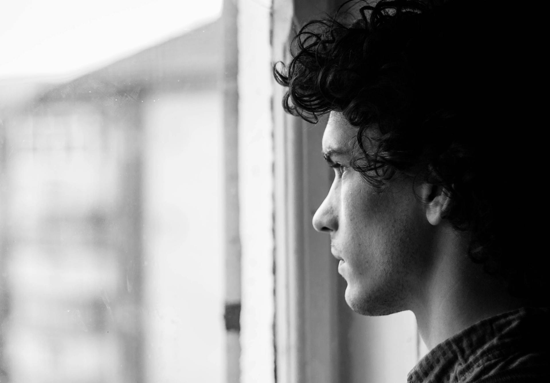 Ein junger Mann schaut aus dem Fenster | Quelle: Pexels