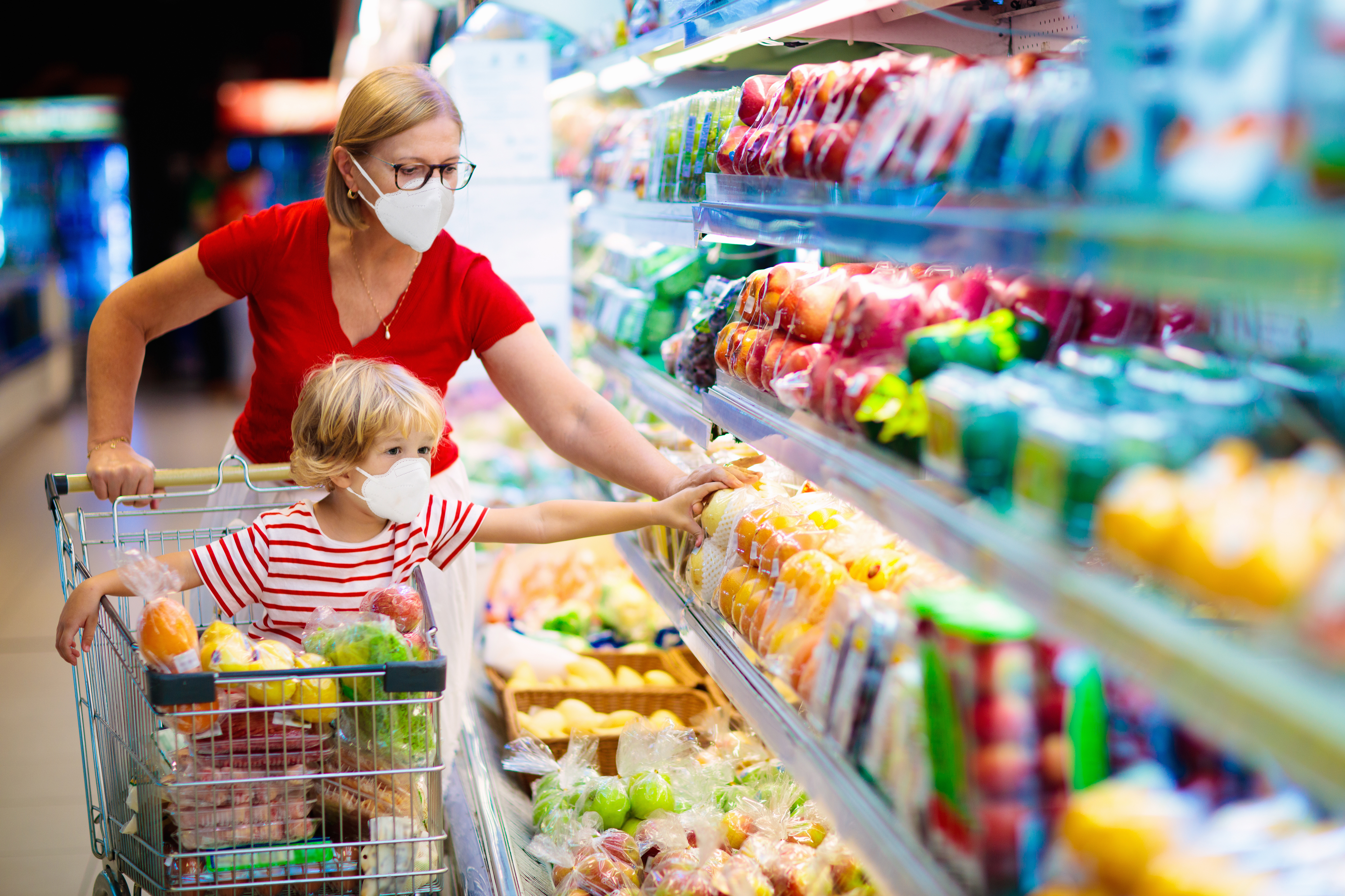Mutter und Sohn tragen Gesichtsmasken beim Einkaufen in einem Supermarkt | Quelle: Shutterstock